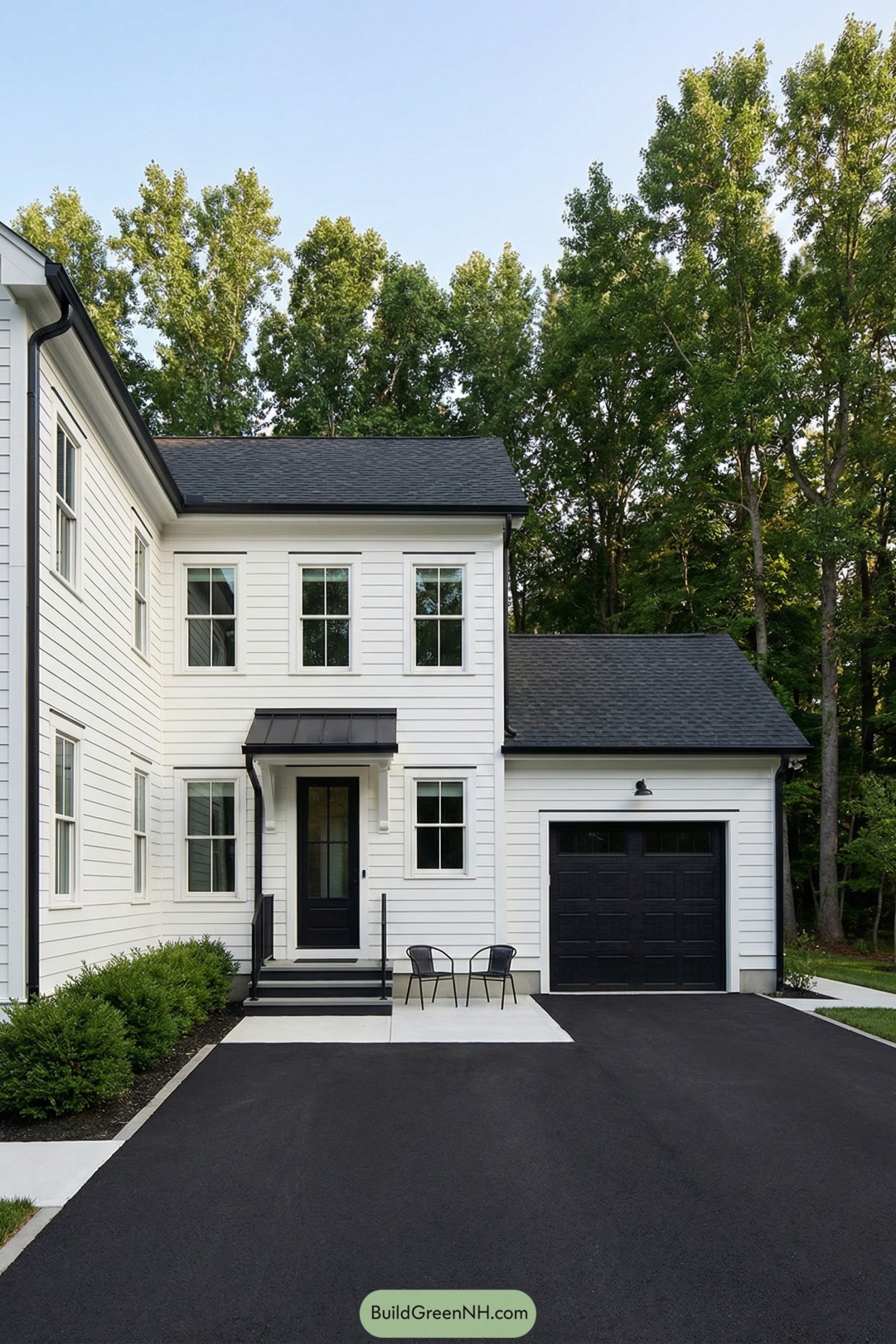 White two story home with black roof door and garage beside a simple paved courtyard