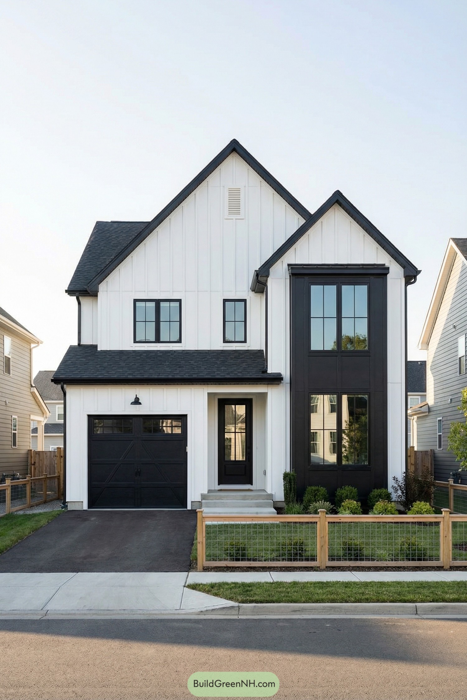 Black and white modern farmhouse with tall gables, attached garage, and fenced front yard
