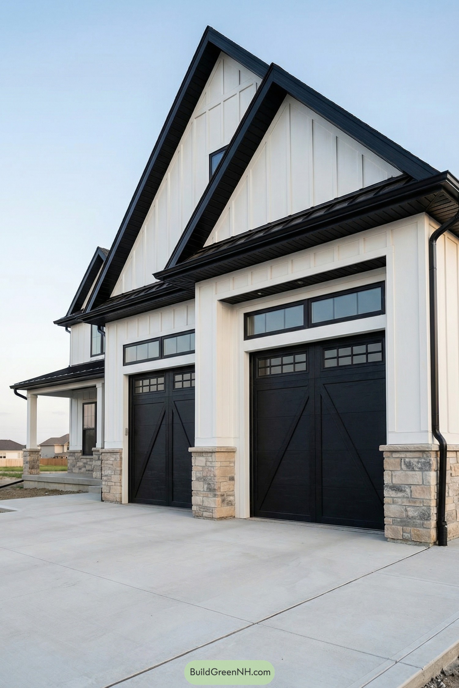 Modern farmhouse exterior with tall white gables, black trim, and dual black garage doors over stone bases