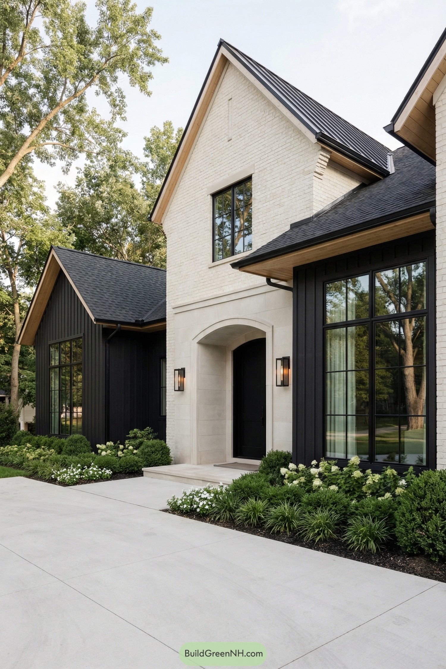 Modern black and white gabled house exterior with tall windows and lush foundation plantings