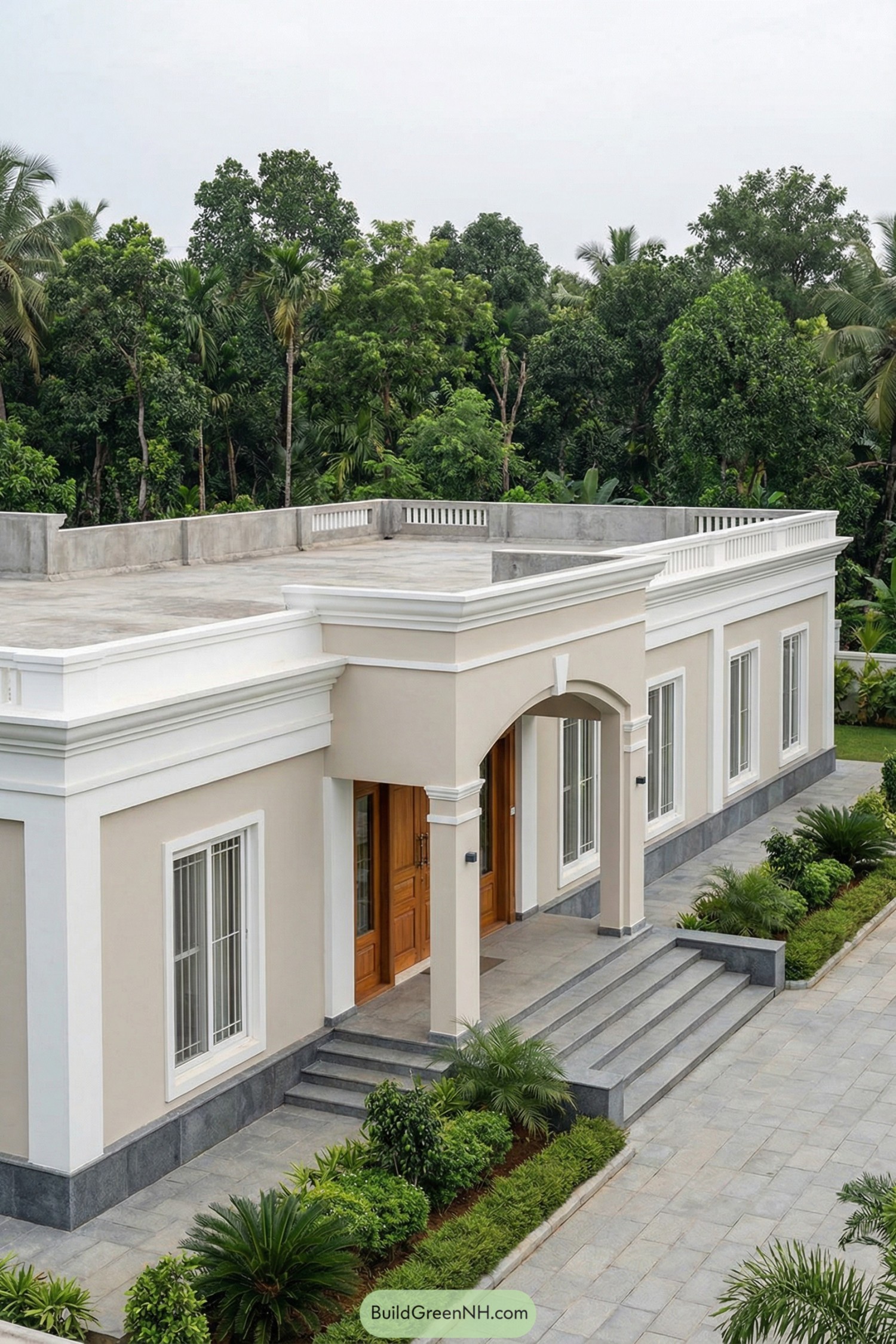 Single story beige bungalow with flat roof terrace, arched entry, and tall white windows framed by lush greenery