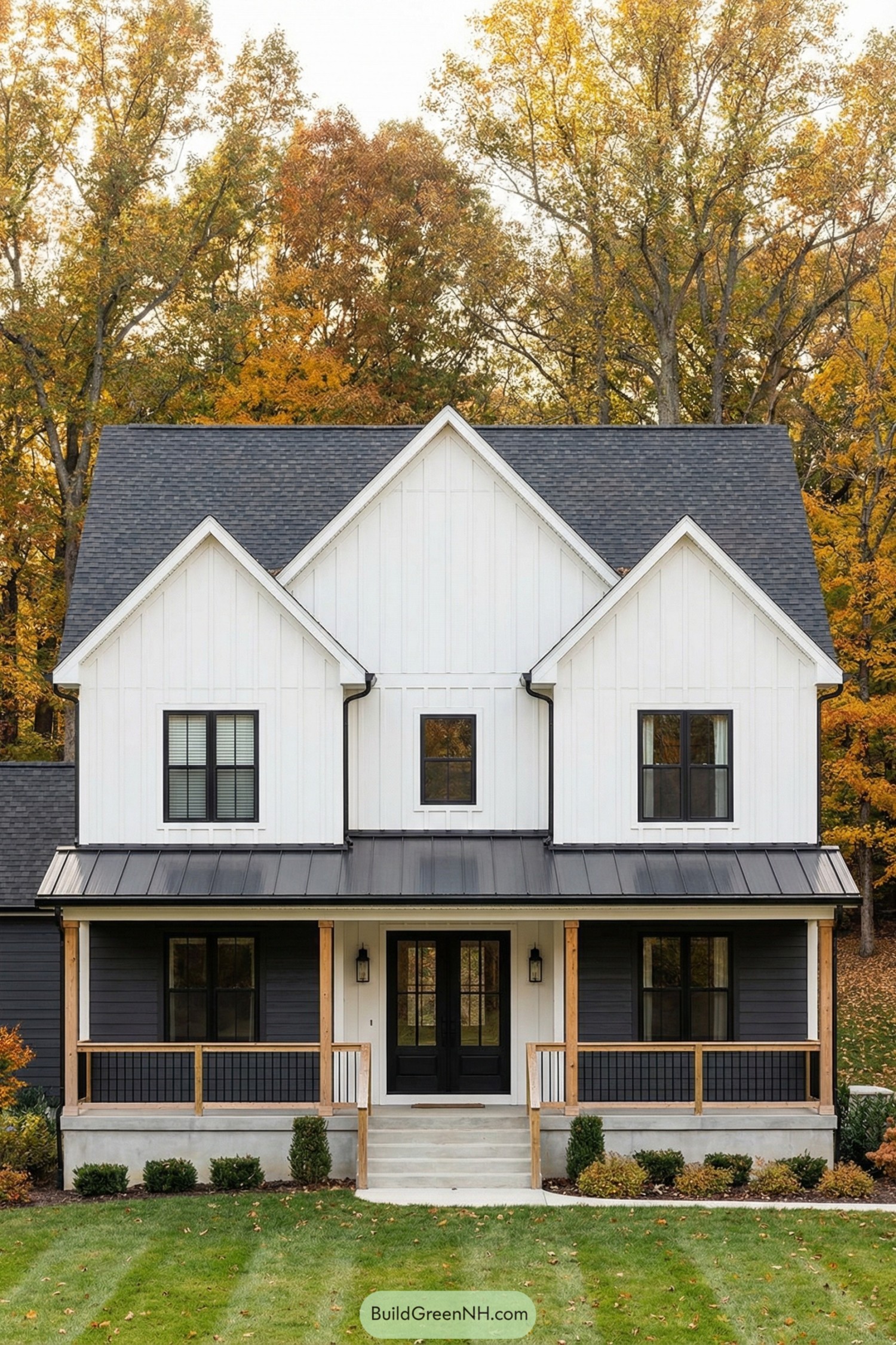 White and charcoal colonial style home with triple front gables and a covered porch set against fall trees