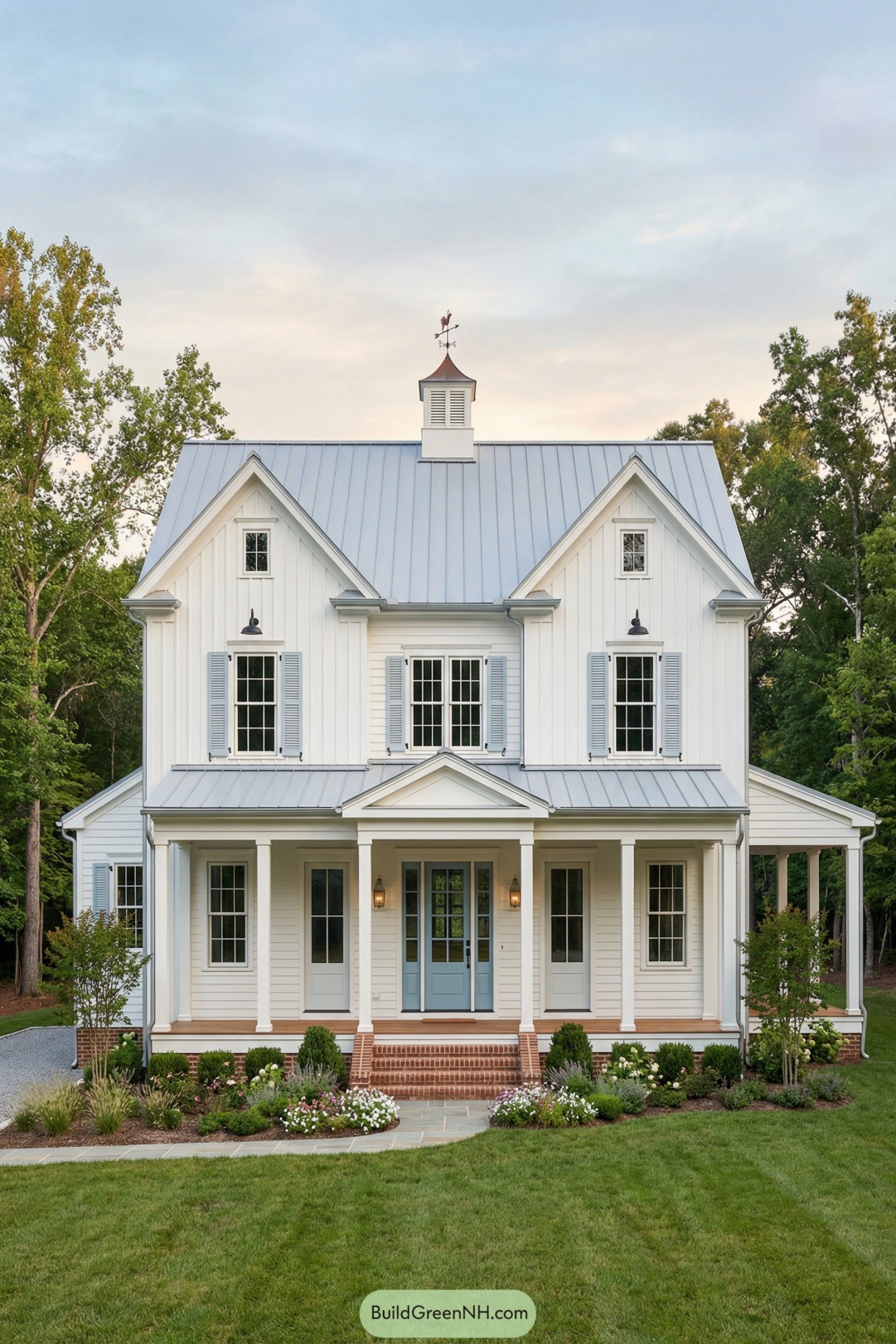 White colonial style barndominium with blue metal roof and front porch