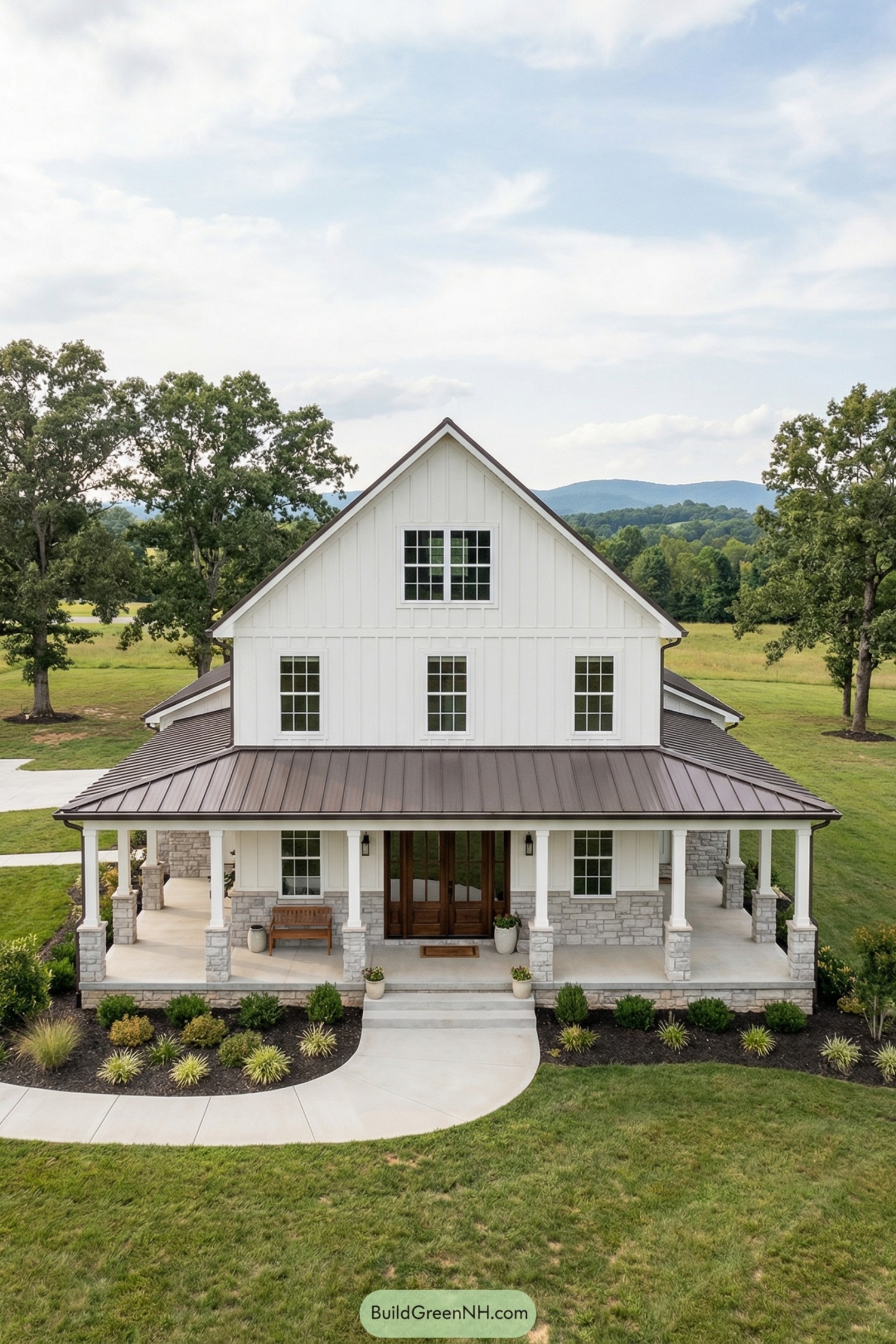 White board and batten colonial barndominium with deep wraparound porch, stone base, and metal roof set in open countryside