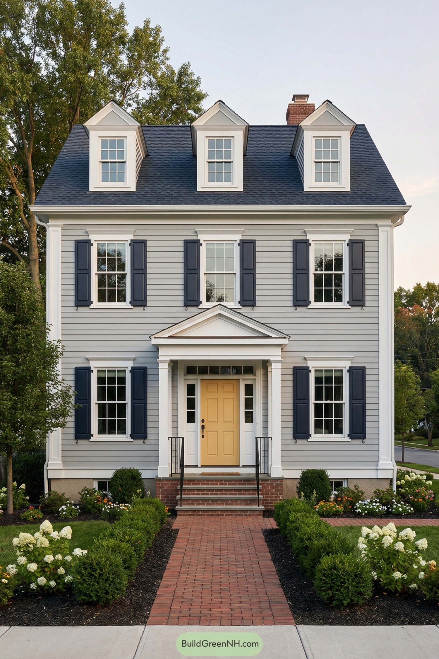 Gray colonial house with navy shutters and a soft yellow front door