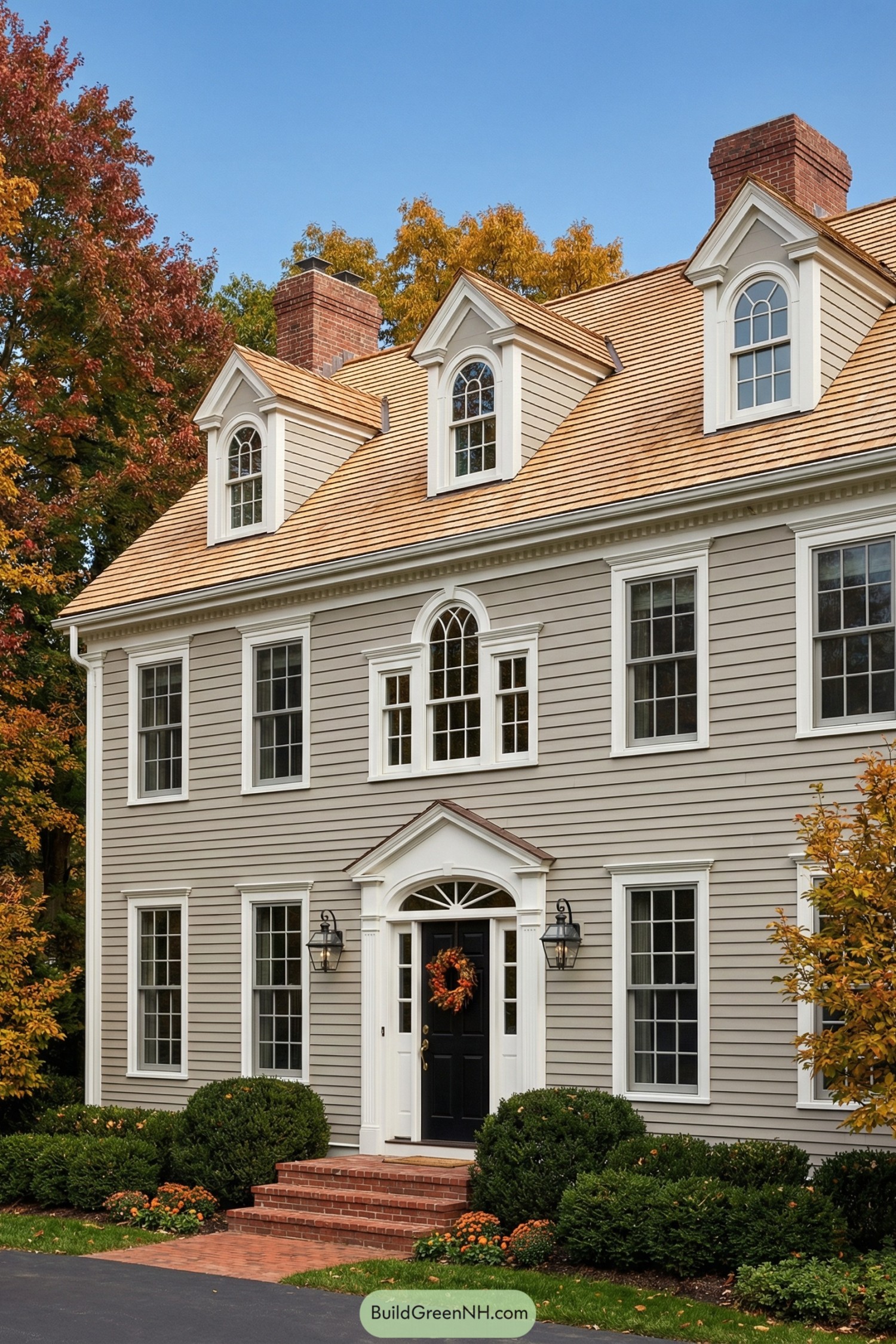 Taupe colonial home with honey shingle roof, white trim, and black front door with brick steps