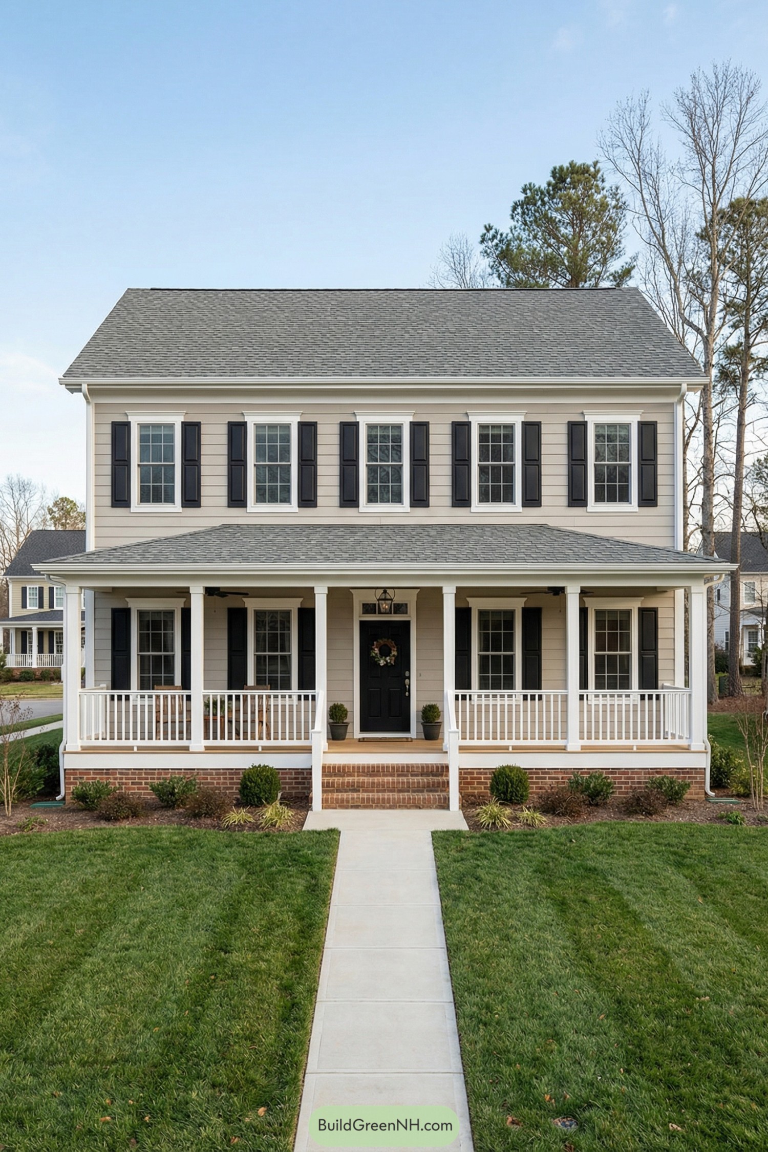 Two story beige garrison colonial with black shutters and full front porch facing a neat green lawn
