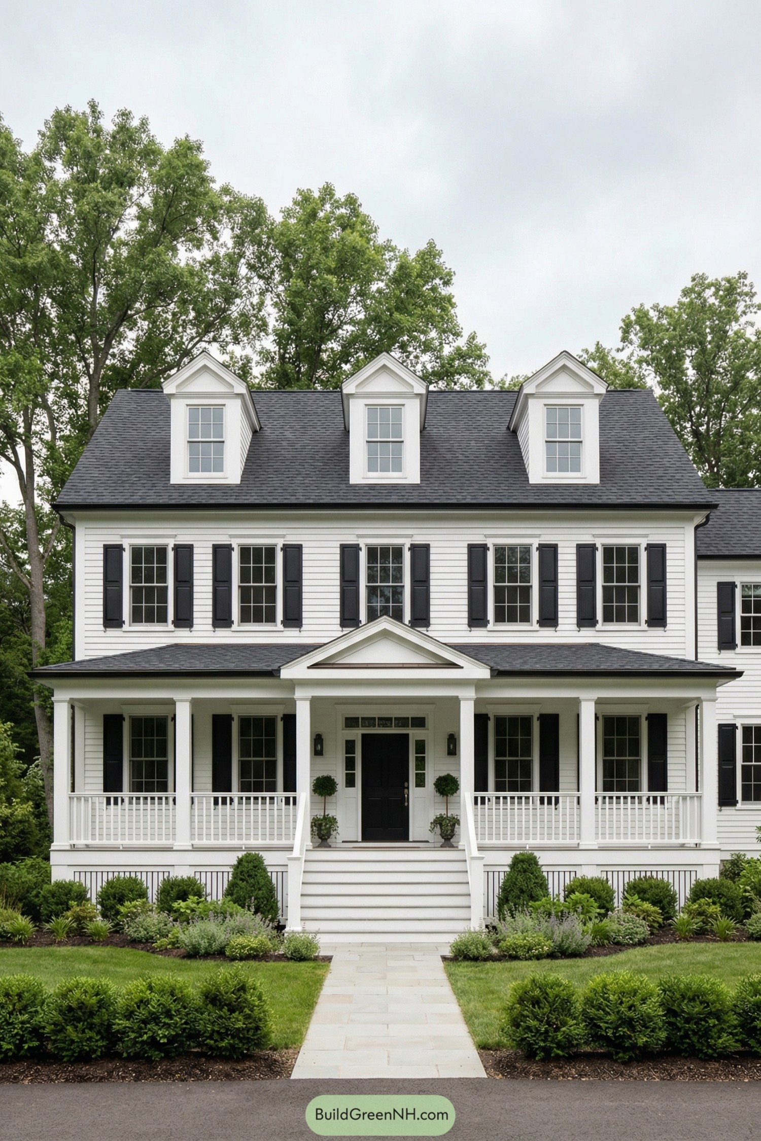 White garrison colonial with black shutters and full front porch surrounded by manicured landscaping