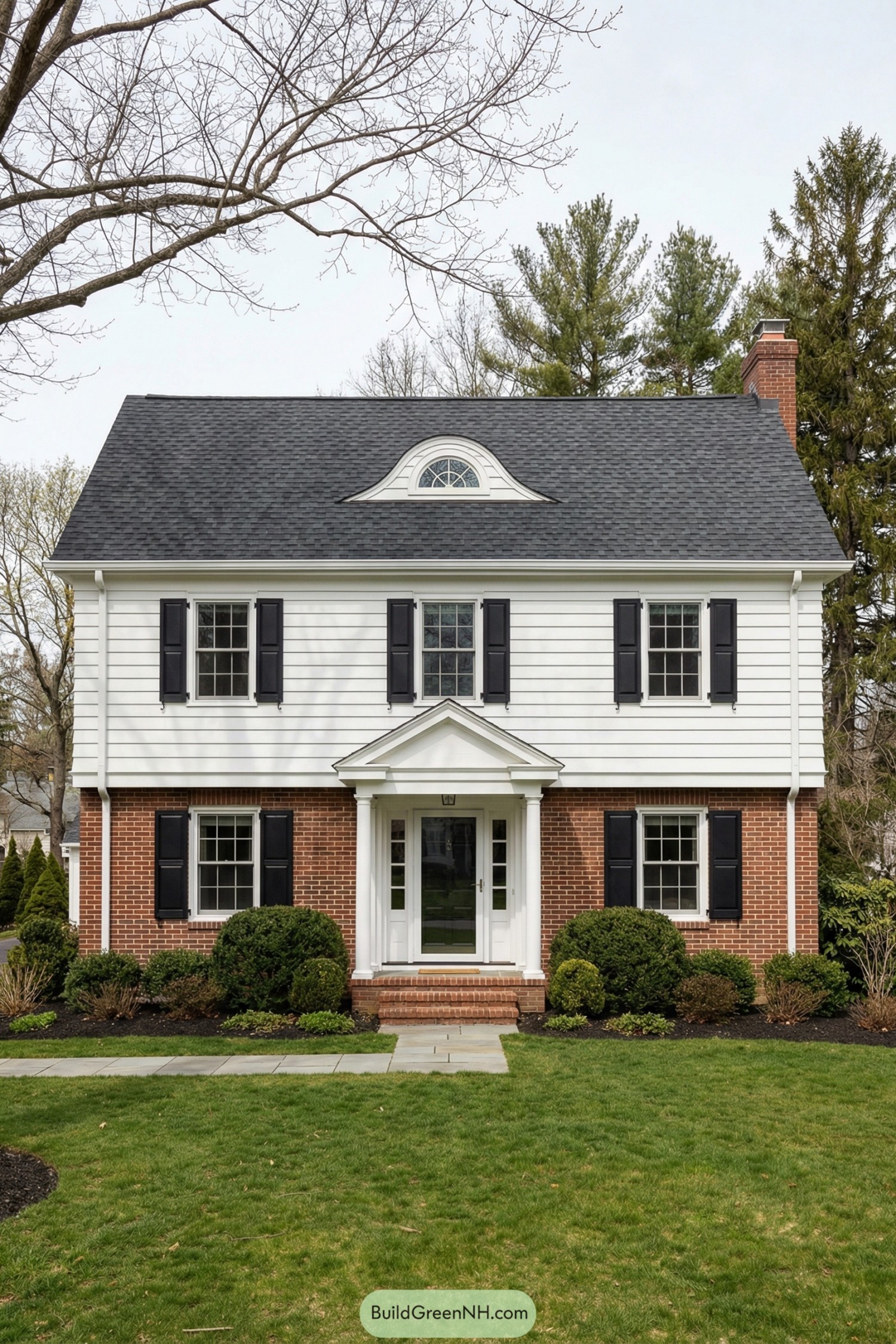Two story garrison colonial with brick base and white siding