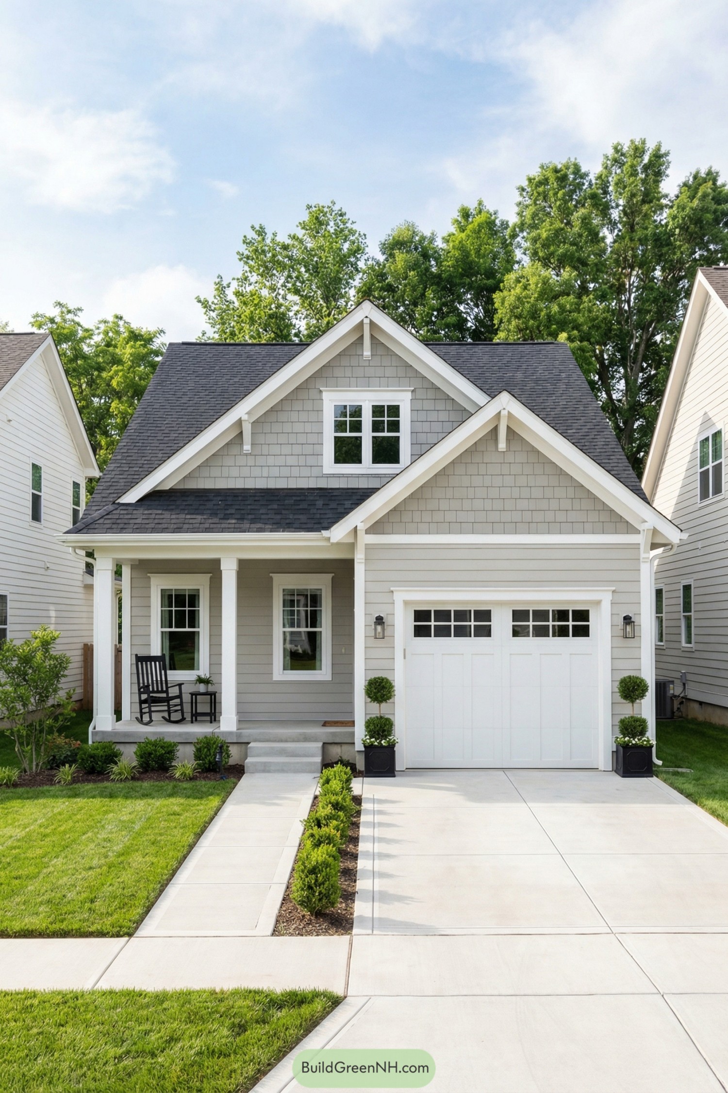 Small gray cottage with white trim and a front porch beside a single-car garage