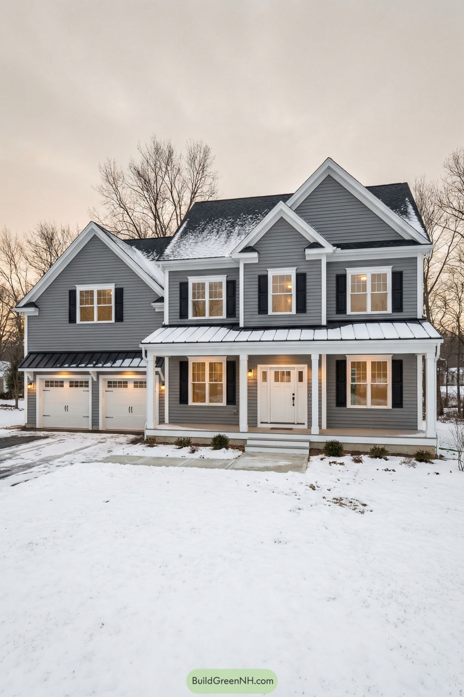 Two story gray house with white trim black shutters and attached double garage in a snowy yard