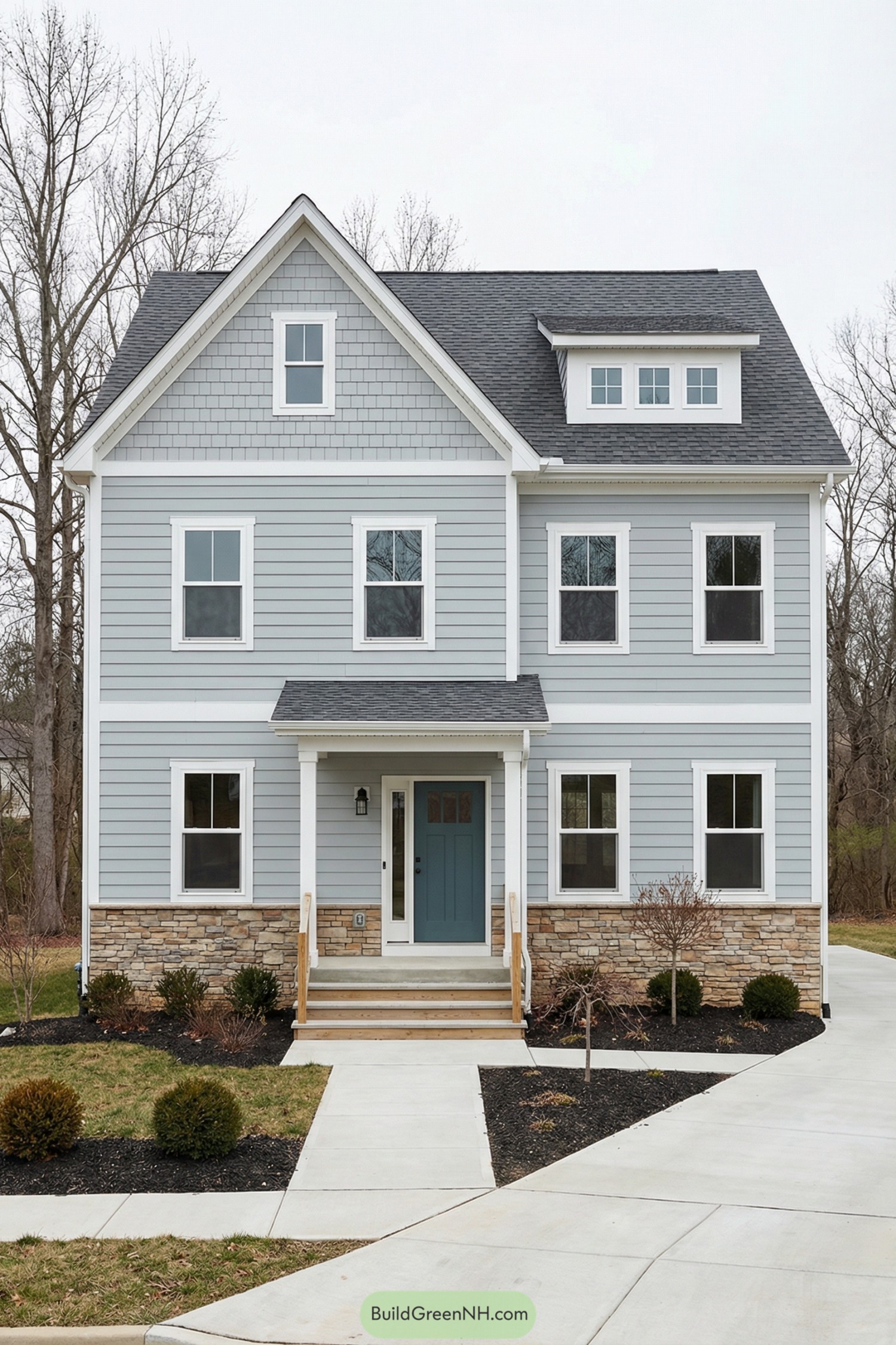 Two story gray house with white trim and stone base featuring a blue front door and simple covered porch
