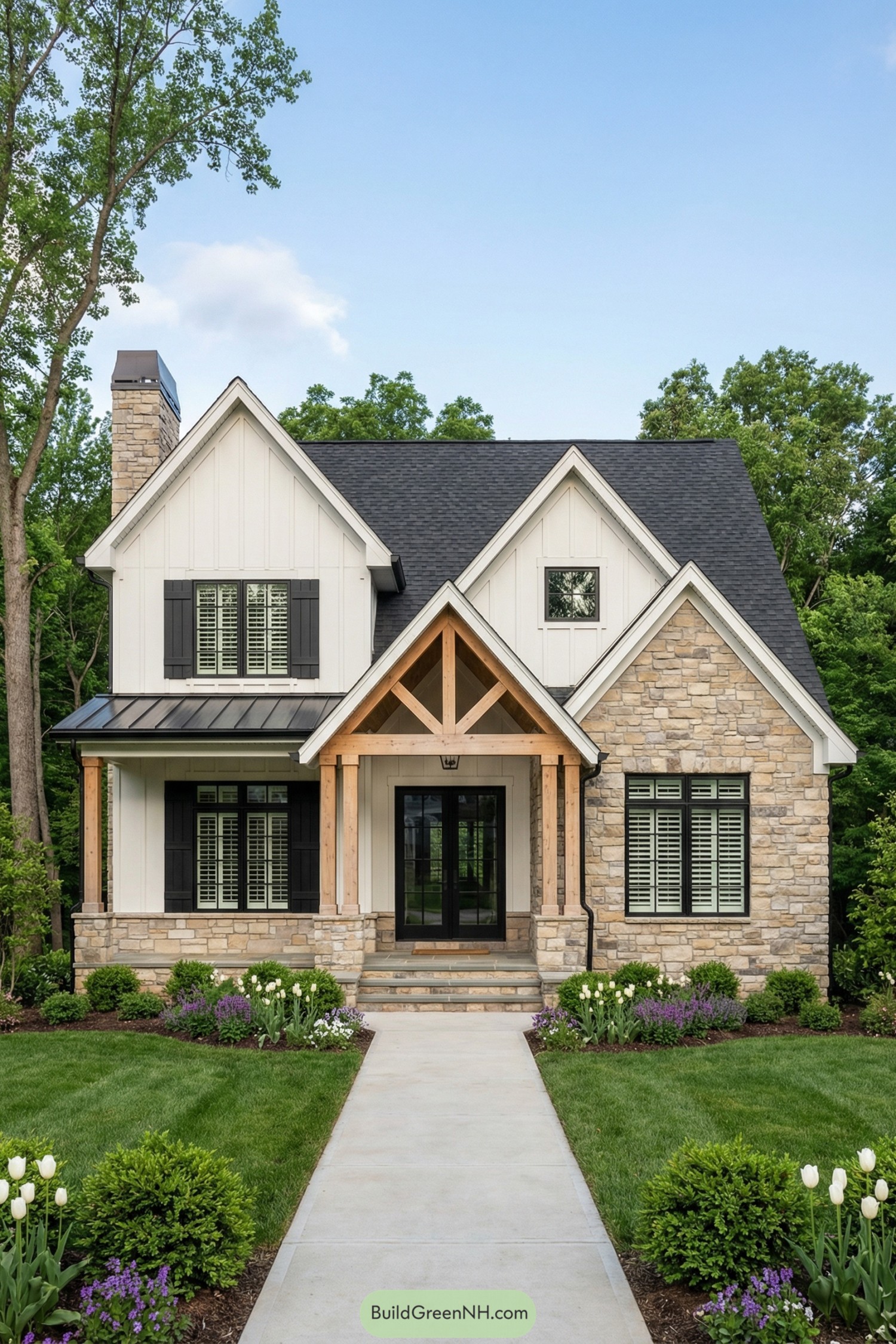 high-res photo of House With Gables, symmetrical modern farmhouse / craftsman facade with multiple front-facing gables, dominant central porch gable flanked by two larger side gables and a smaller upper gable, clean lines and balanced proportions. Exterior colors in crisp white, warm multi-tone beige and gray stone, black window frames and shutters, natural light-wood porch structure, dark charcoal roof. Broad, low-slung one-story massing with projecting wings and deep gable over the entry, rectangular footprint with subtle step-backs. Walls in vertical white board-and-batten siding with a stone water table, right front wing in full stone veneer, upper gable fields in white staggered shingle siding, neatly trimmed white fascia and soffits. Roofing in dark charcoal architectural asphalt shingles on moderately pitched gables, small black metal shed roof sections over side porch areas, stone chimney with metal cap rising behind the left wing. Windows in black-framed divided-light style, mostly rectangular double-hung or casement units, some with white interior muntins and black louvered shutters, consistent rhythm along the facade. Central front door as black-framed double French doors with multiple glass panes and sidelights, set under the main porch gable. Entry porch with stone-clad piers, natural timber posts and decorative truss, simple black hanging lantern, concrete or stone porch floor, small seating area visible. Straight gray concrete walkway leading from foreground to porch steps, edged by layered planting beds and low stone edging at the house base. Landscaping with lush green lawn, curved foundation beds filled with rounded boxwood shrubs, white tulip clusters, purple flowering perennials, low grasses, and groundcover, all in fresh, well-tended appearance. Surrounding environment with tall mature trees framing both sides, dense green foliage backdrop, open sky above. Setting in clear daylight with soft, even lighting, vivid blue sky and a few soft clouds, front-on composition centered on the house, picture-perfect suburban or semi-rural scene. single real-life photo, high-resolution, architectural photography, soft lighting, cinematic composition, strictly no collages