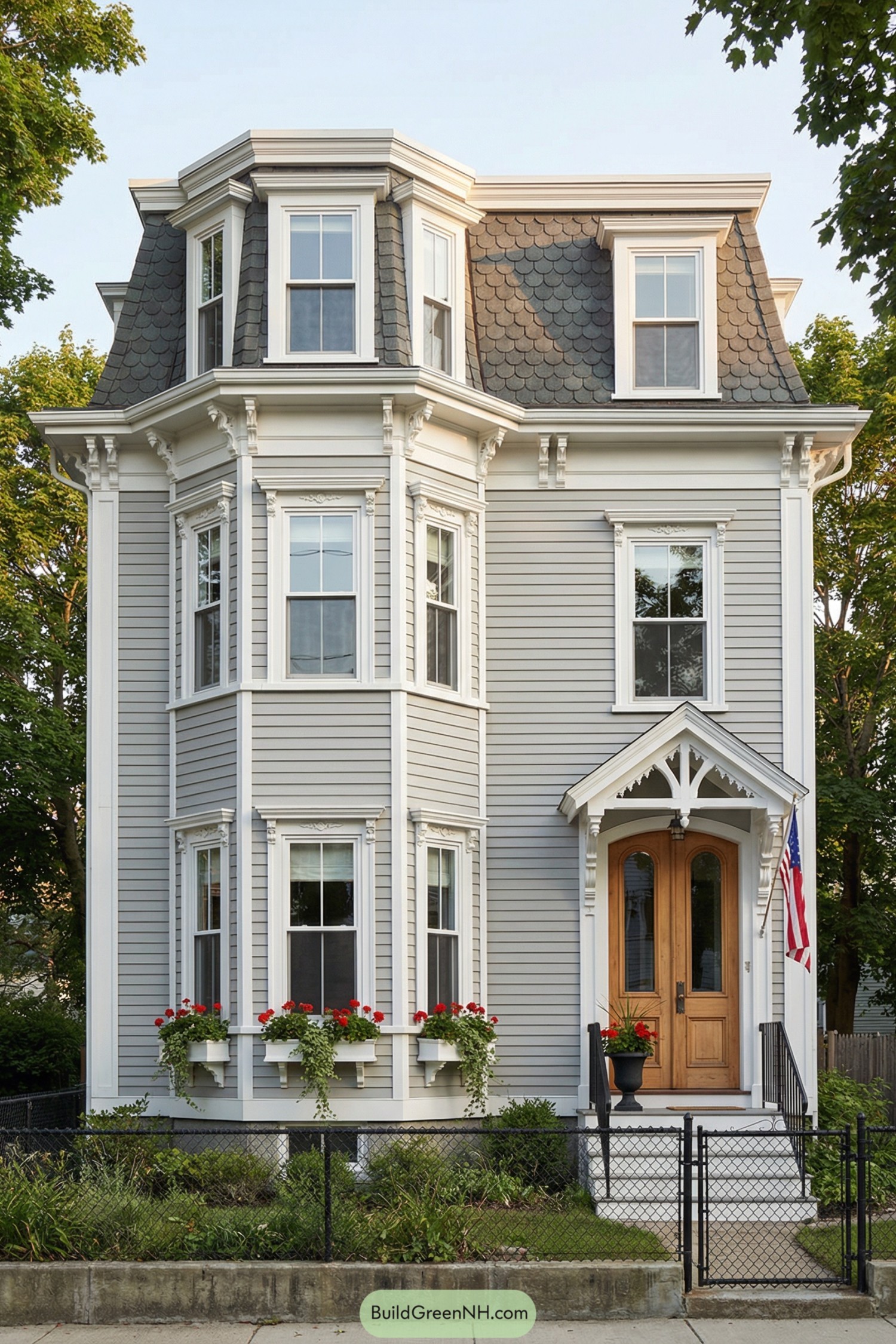 Tall gray mansard house with ornate bays and wood entry door
