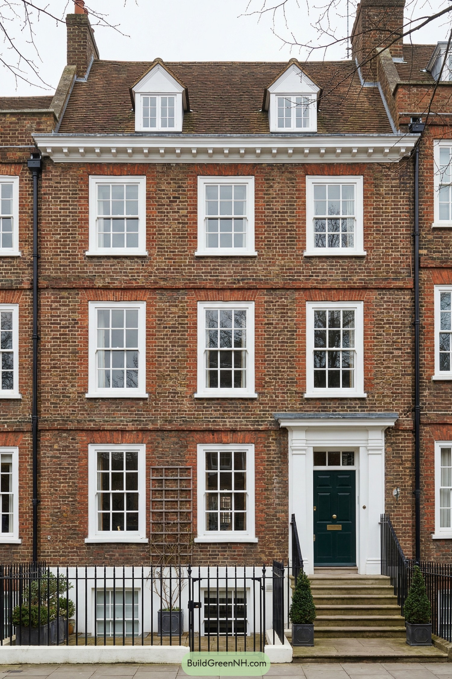 Traditional redbrick London townhouse with white-trimmed sash windows and a dark green front door