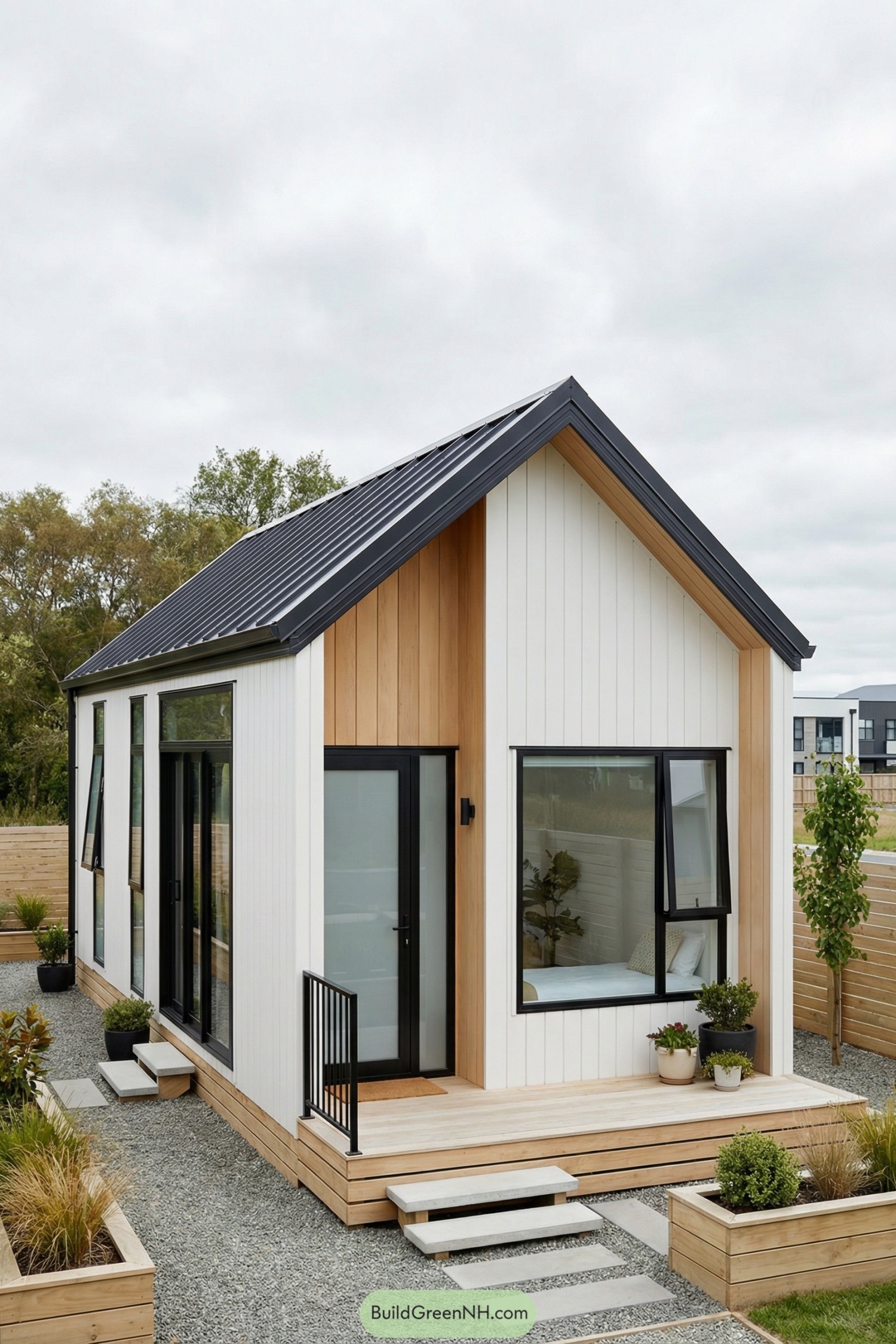 Modern tiny house with black metal gable roof, white and wood siding, and large black framed windows