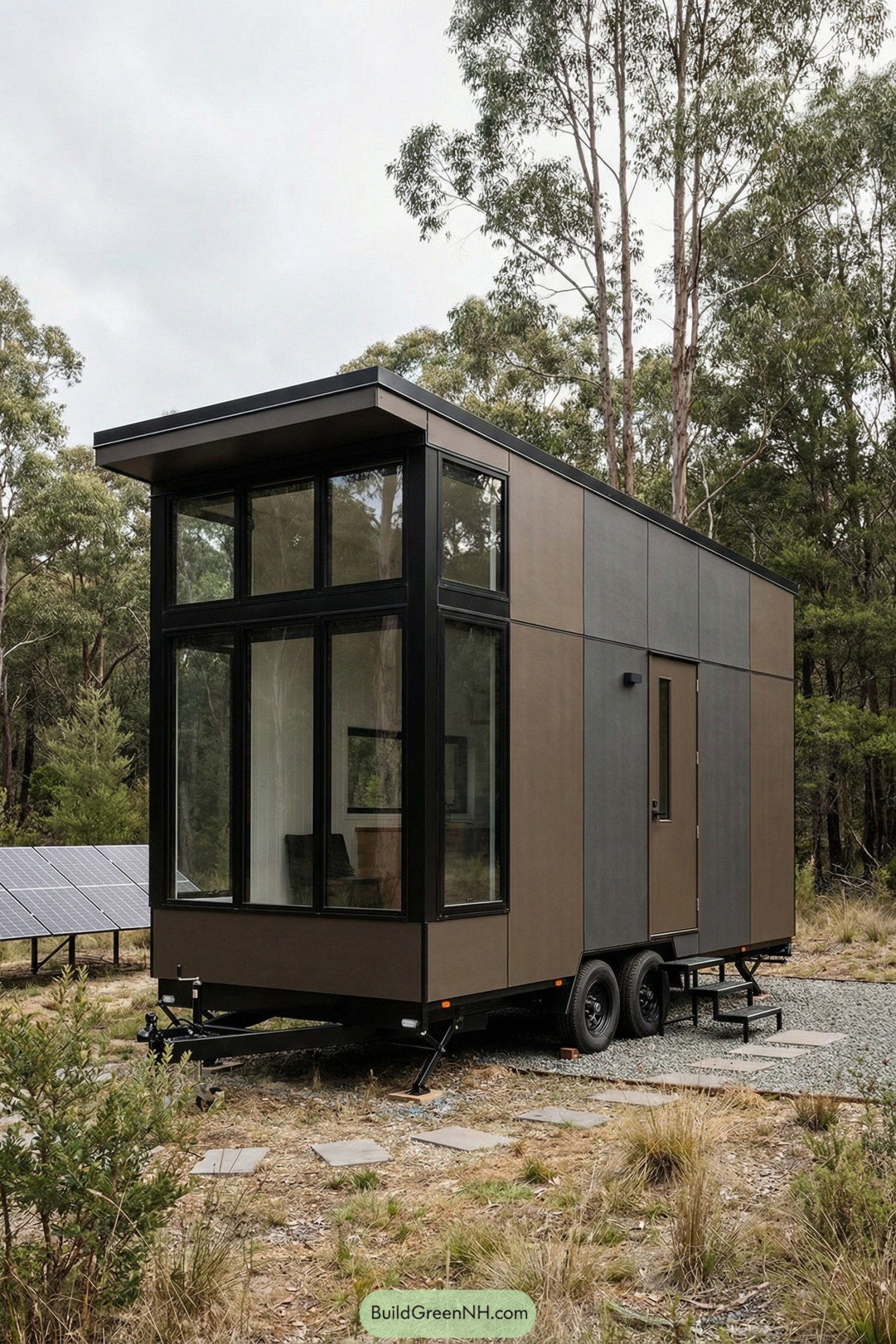 Modern brown tiny house on wheels with tall glass facade parked in a forest clearing