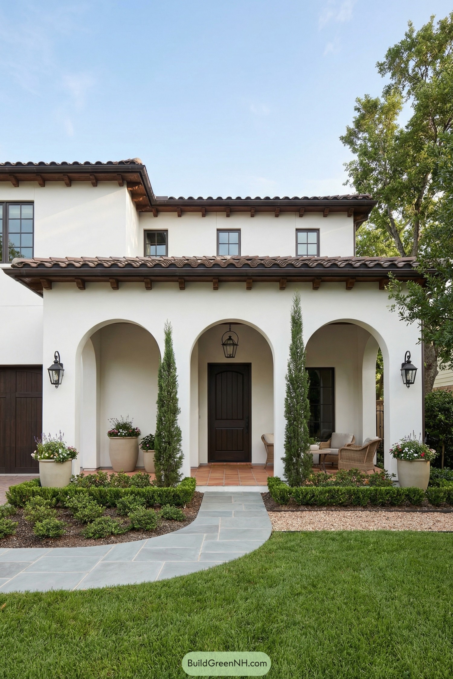 White stucco Spanish villa with arched porch, terracotta roof, and manicured front garden