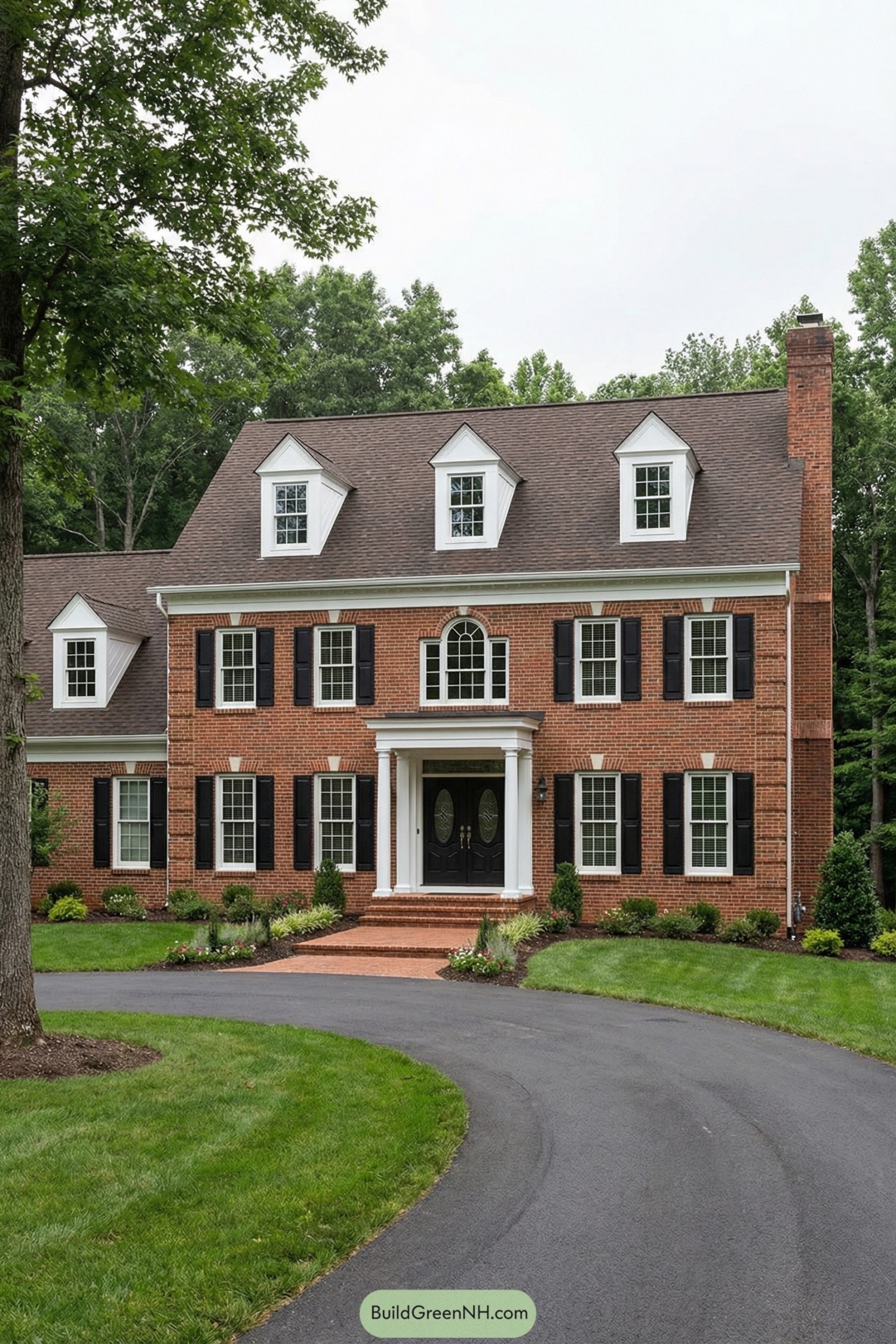 Red brick colonial house with black shutters, white trim, and a columned entry framed by a curved driveway