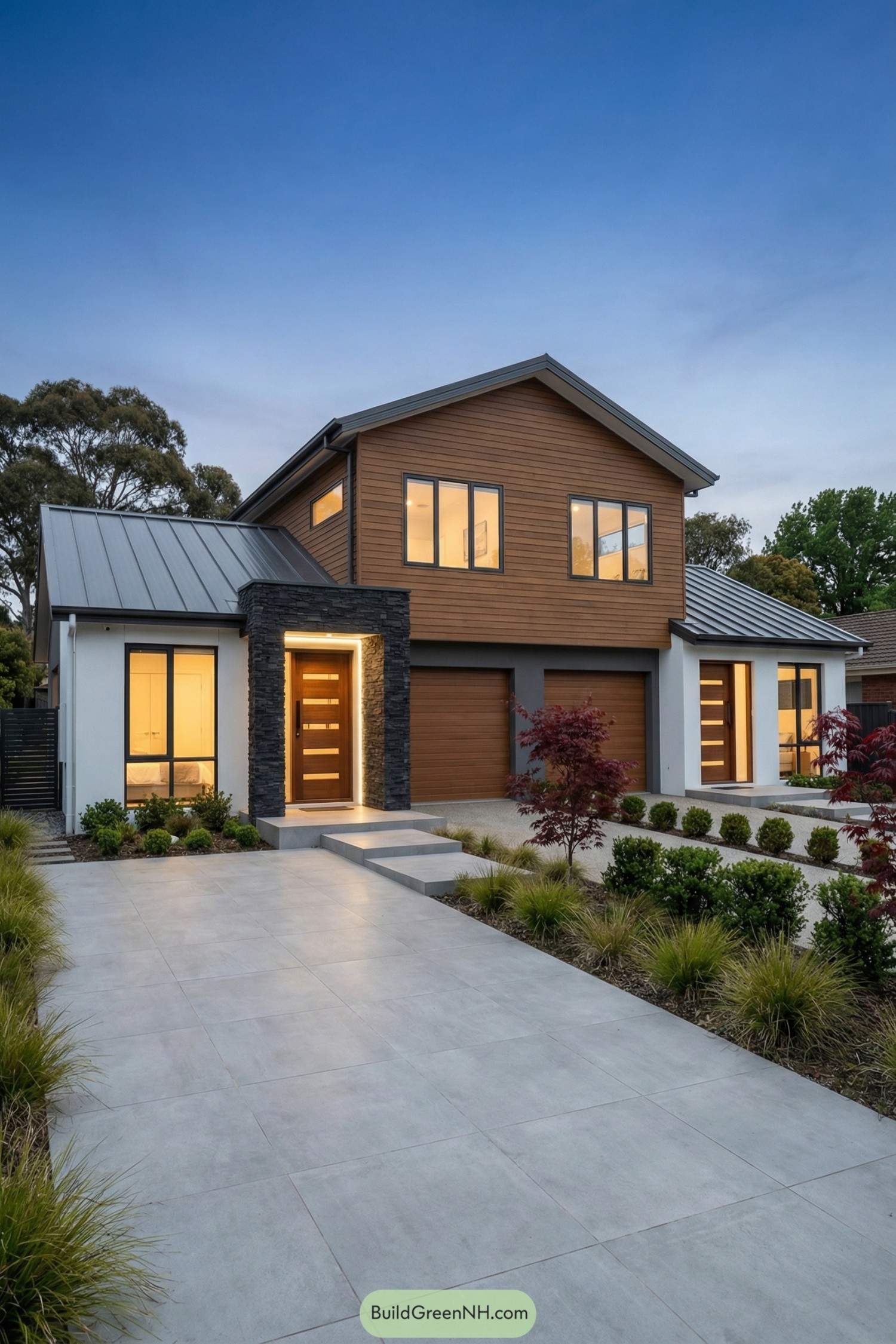 Modern duplex with timber upper level metal roofing and stone framed entry at dusk