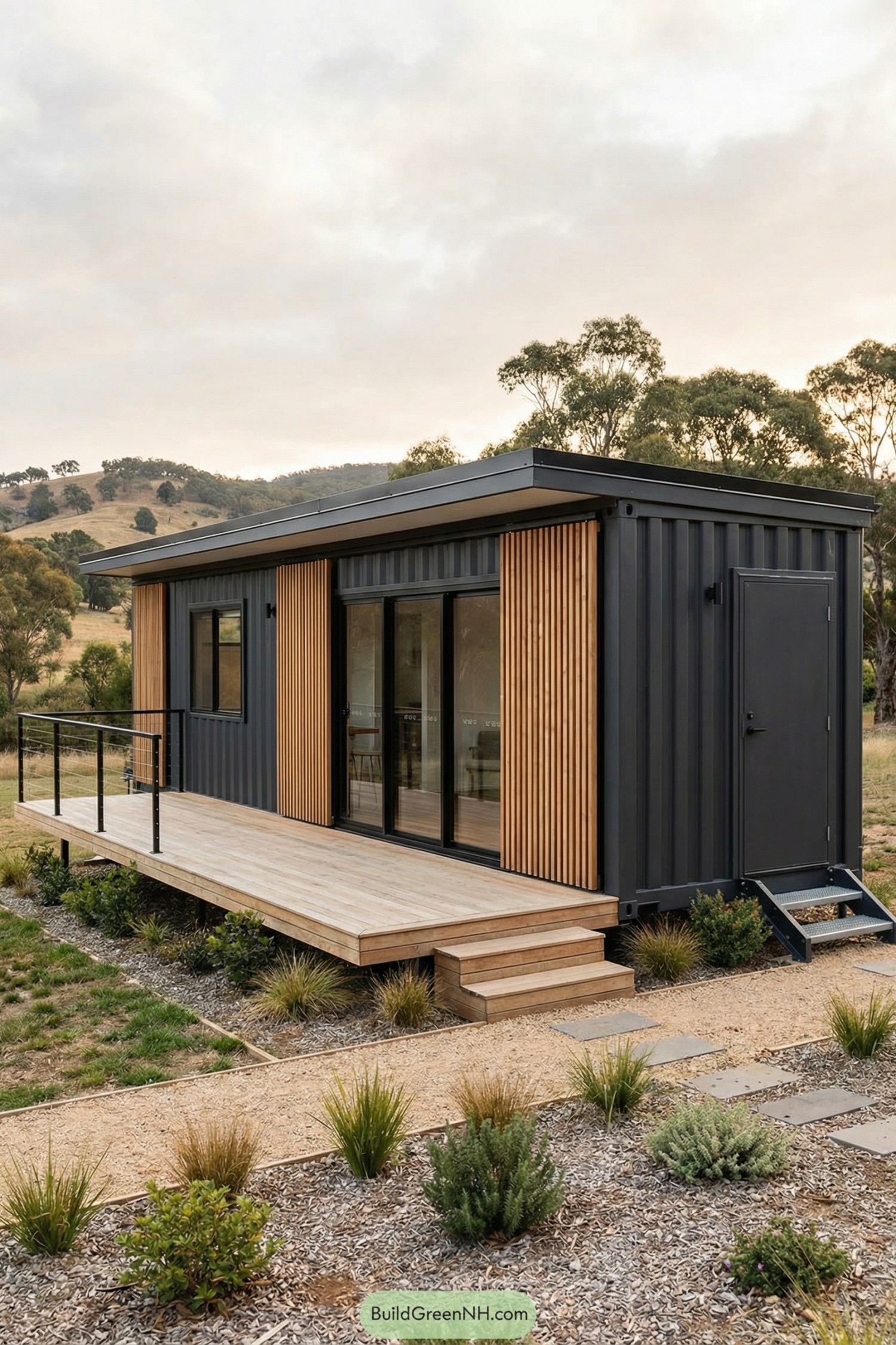 Dark container tiny house with vertical wood cladding and raised deck in an open landscape