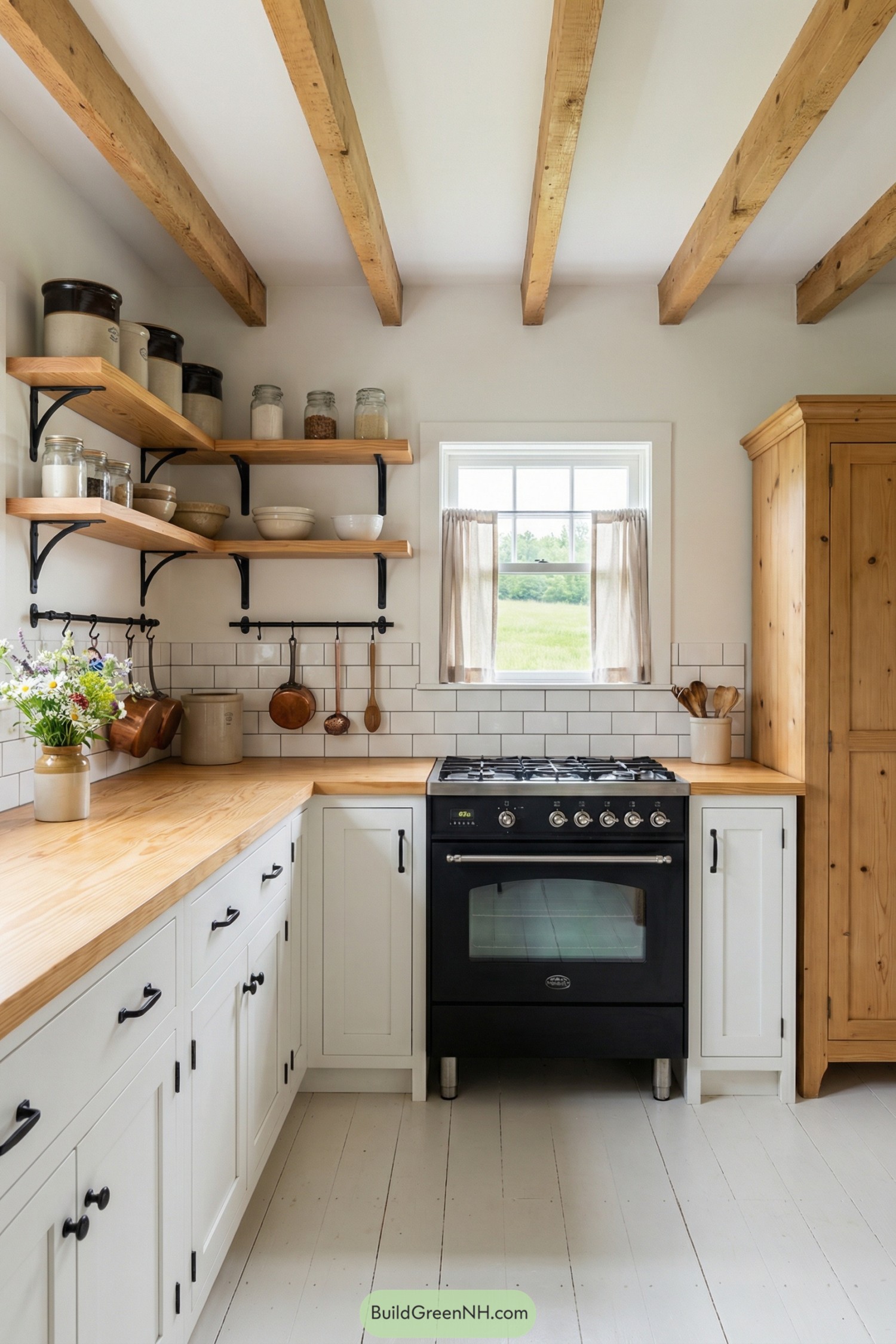 Small country kitchen with exposed wood beams, white cabinets, and black range