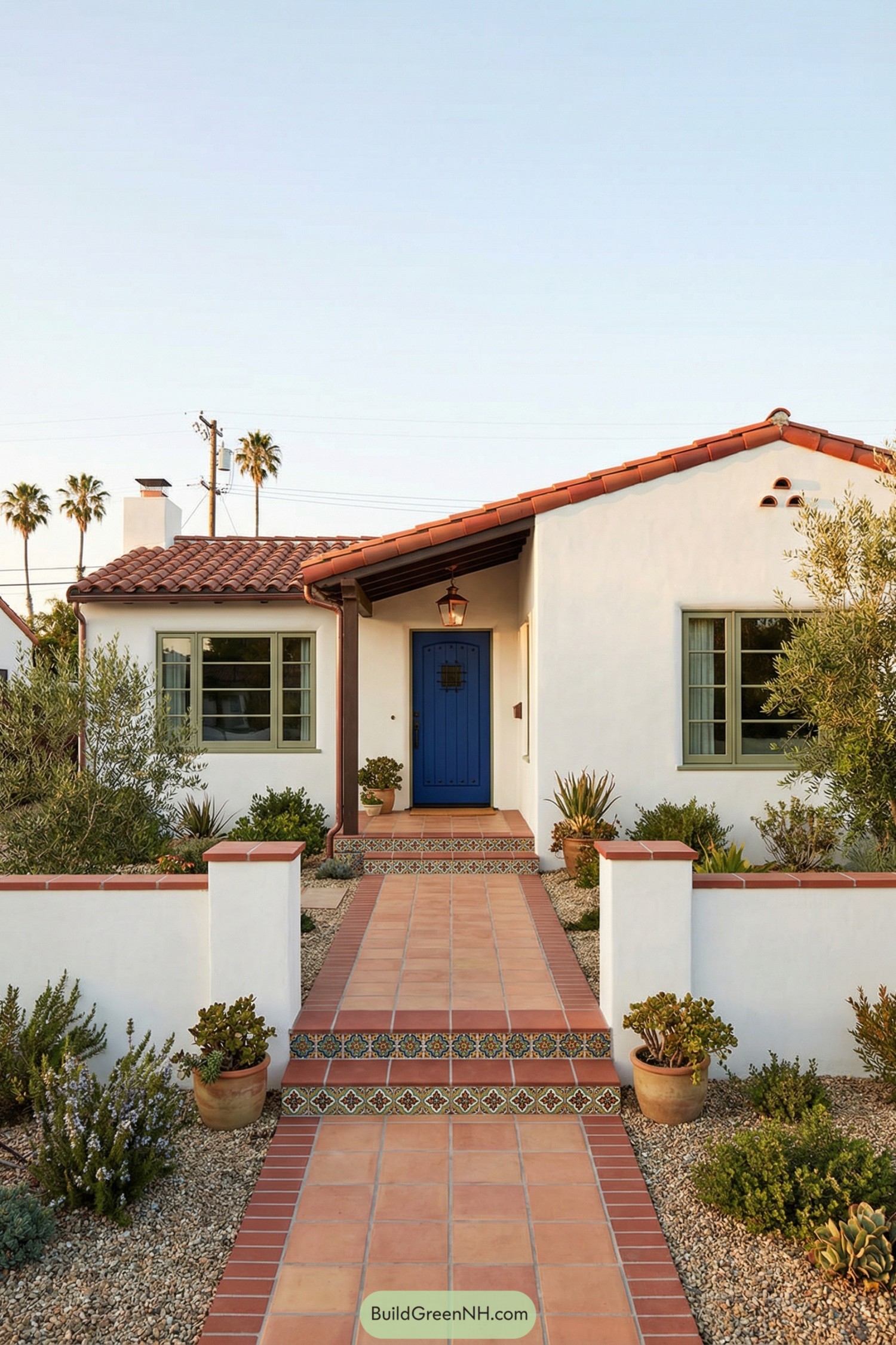 Small white stucco Spanish house with red tile roof and bright blue front door