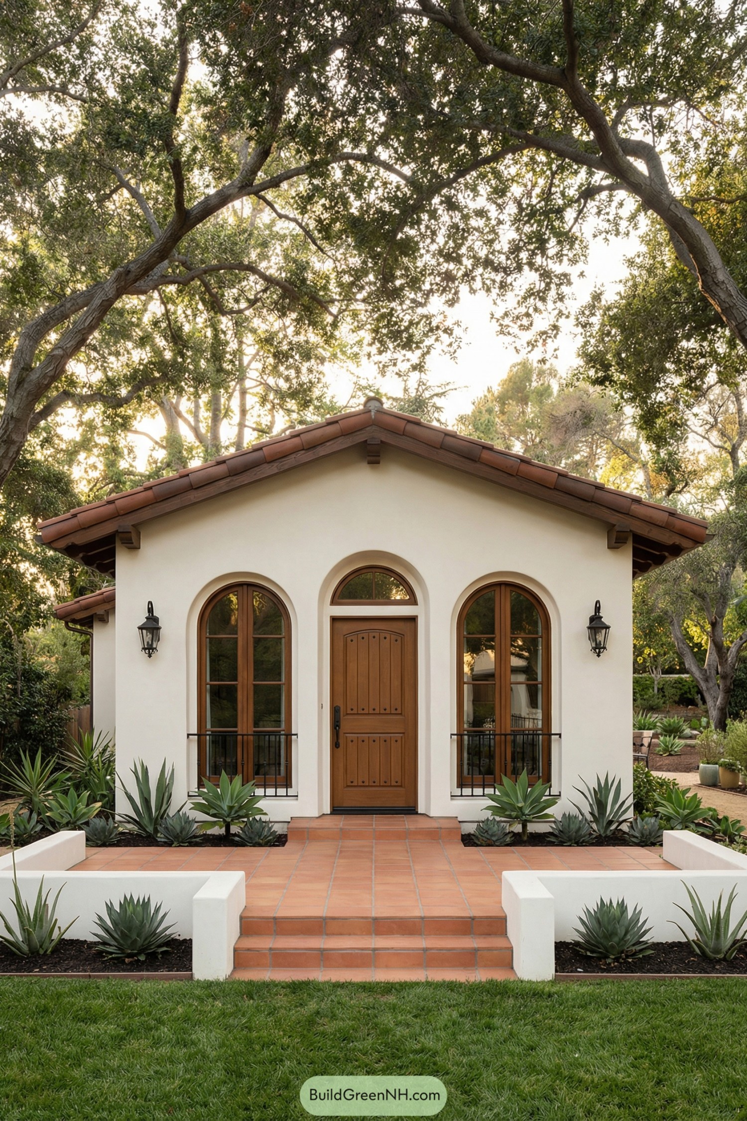 Small white Spanish-style cottage with arched wood door and terracotta entry steps