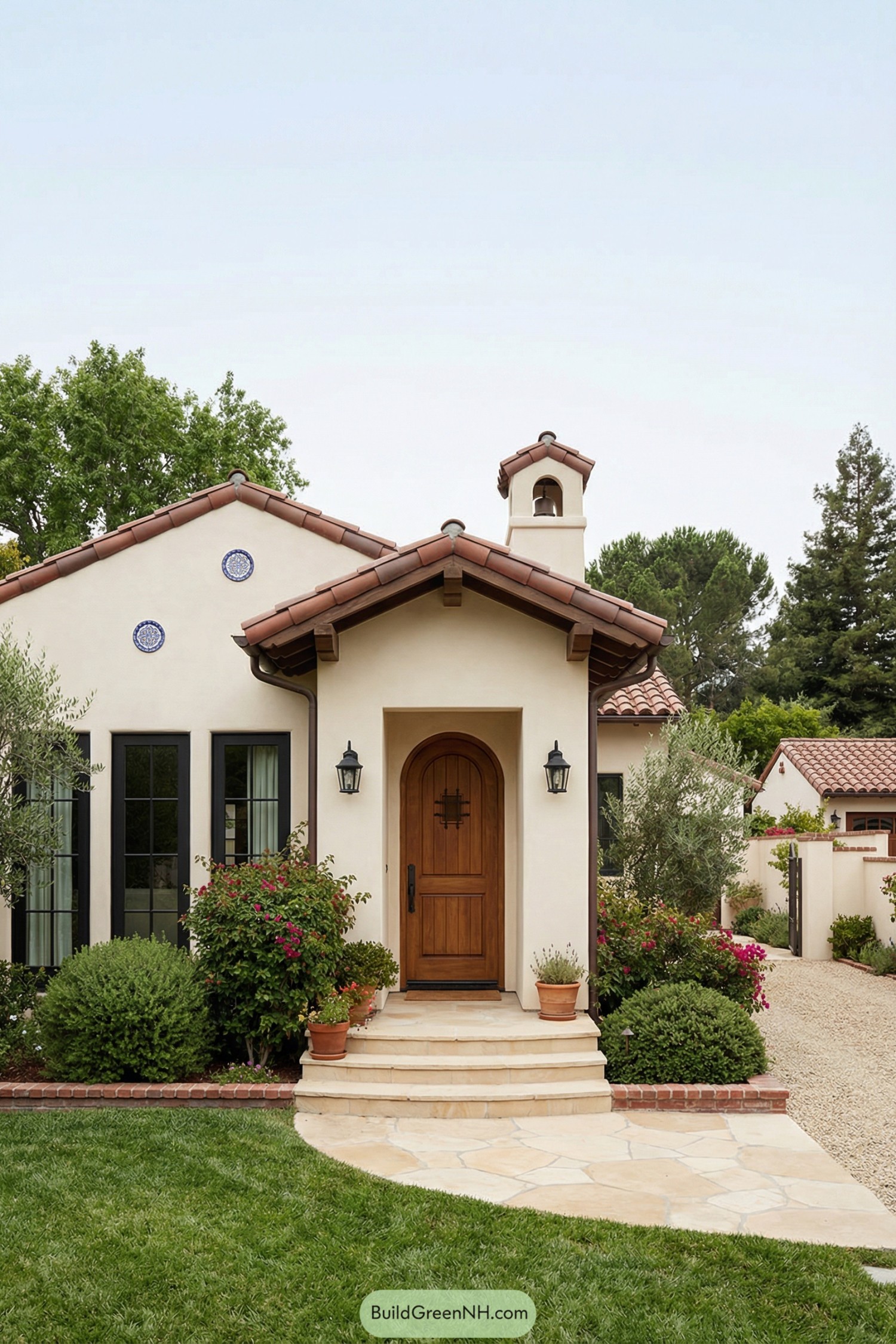 Cream stucco Spanish bungalow with red clay roof and arched wooden door
