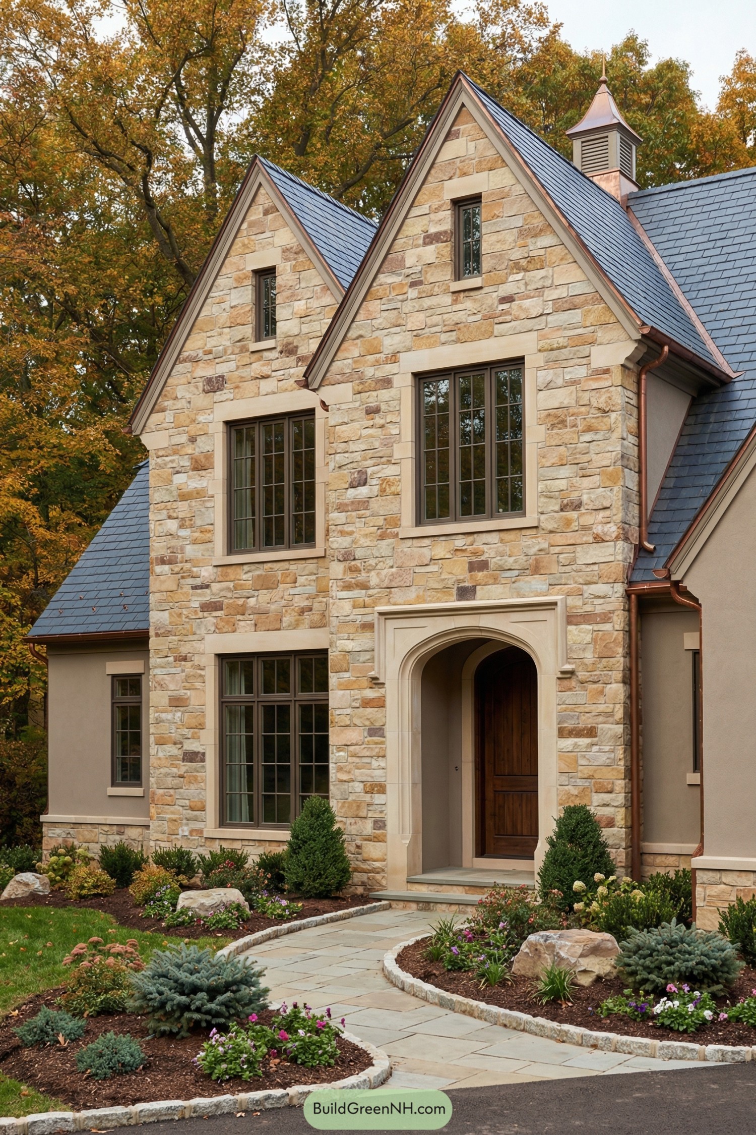 Stone front house with steep gables and curved walkway through landscaped garden beds