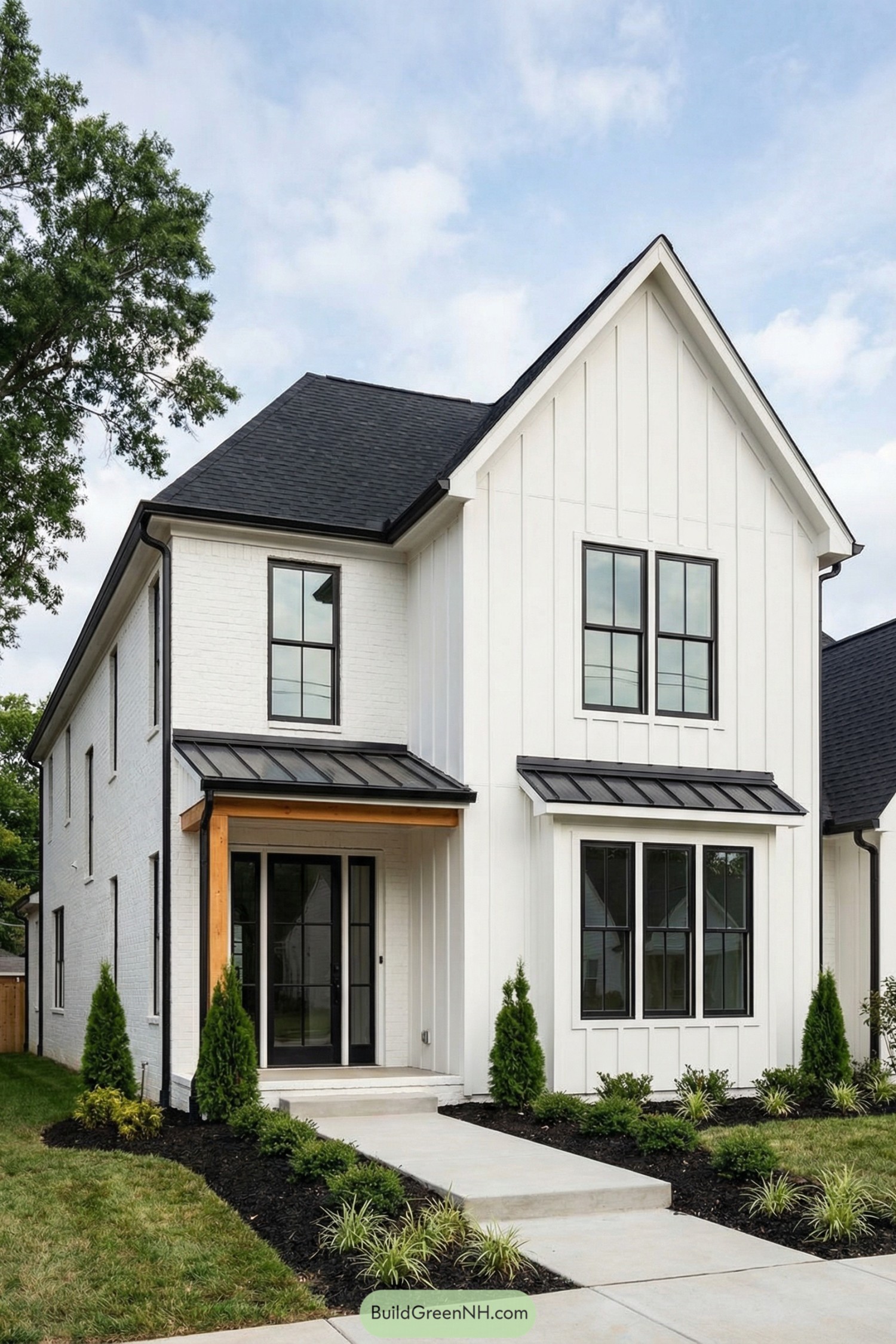 White two story house with black roof and trim surrounded by simple landscaping