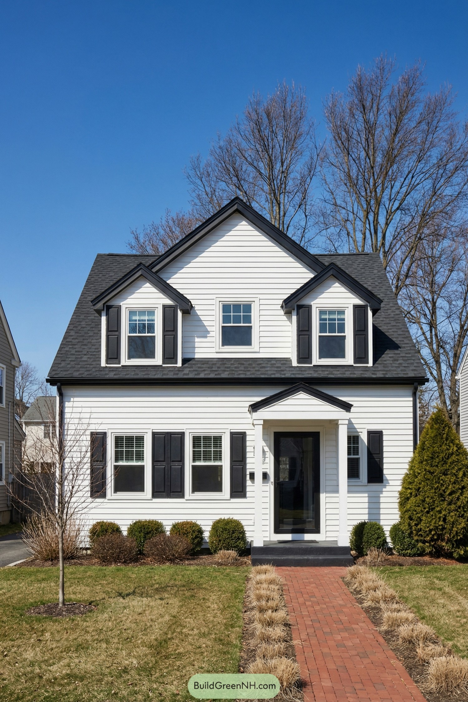 White two-story house with black shutters and gabled roof facing a brick walkway and tidy front yard