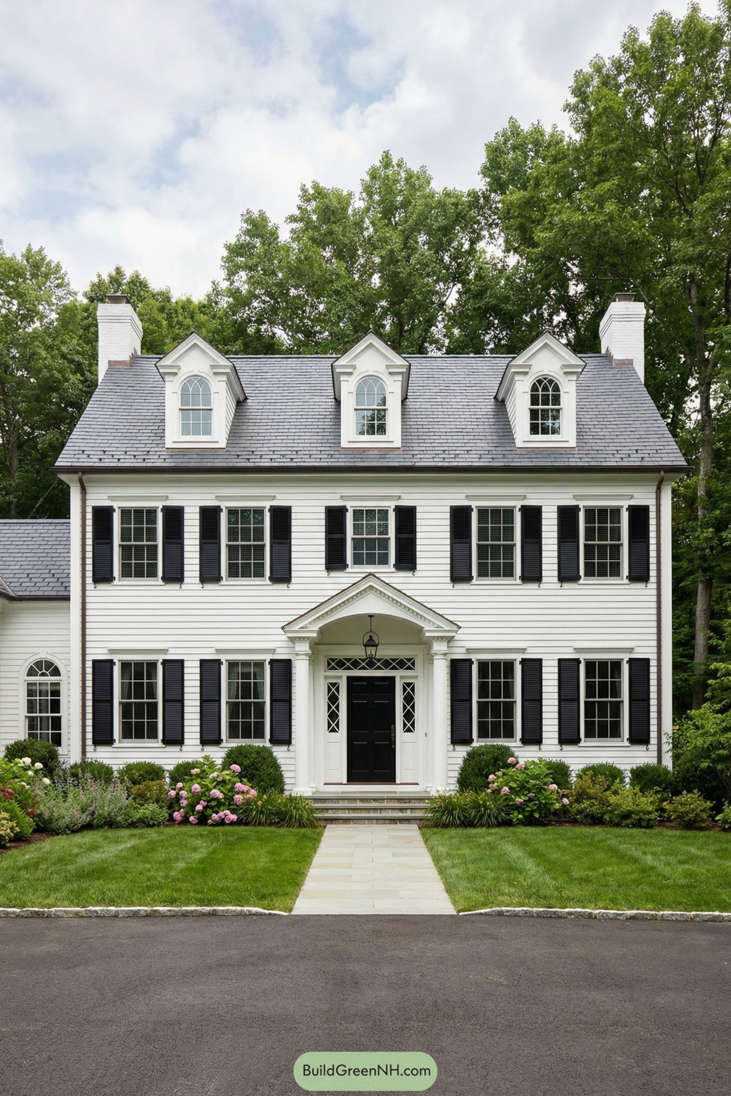 White two story traditional house with black shutters dormer windows and a central columned entry