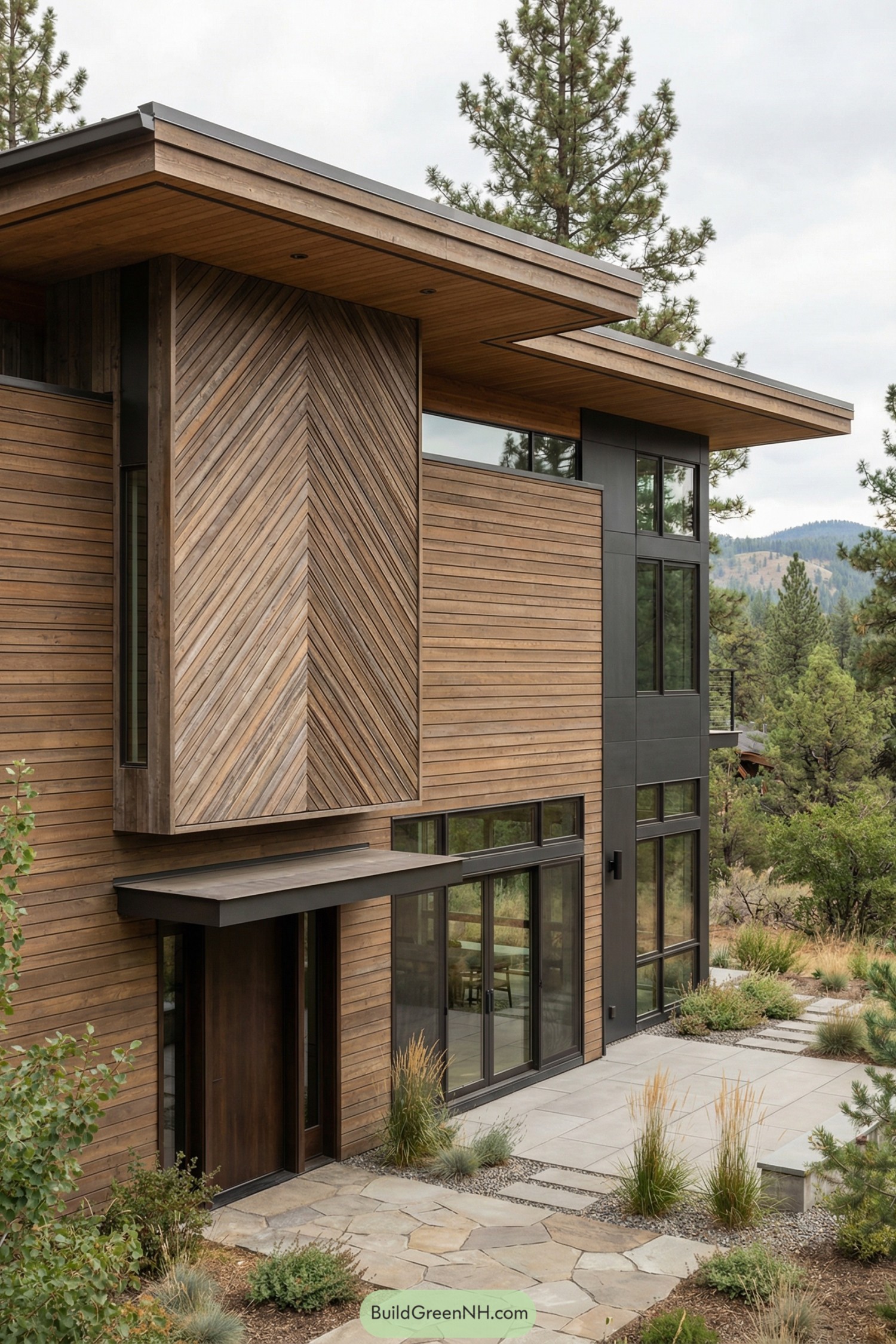 Two story modern home with mixed horizontal and diagonal wood cladding and large dark framed windows facing a mountain landscape