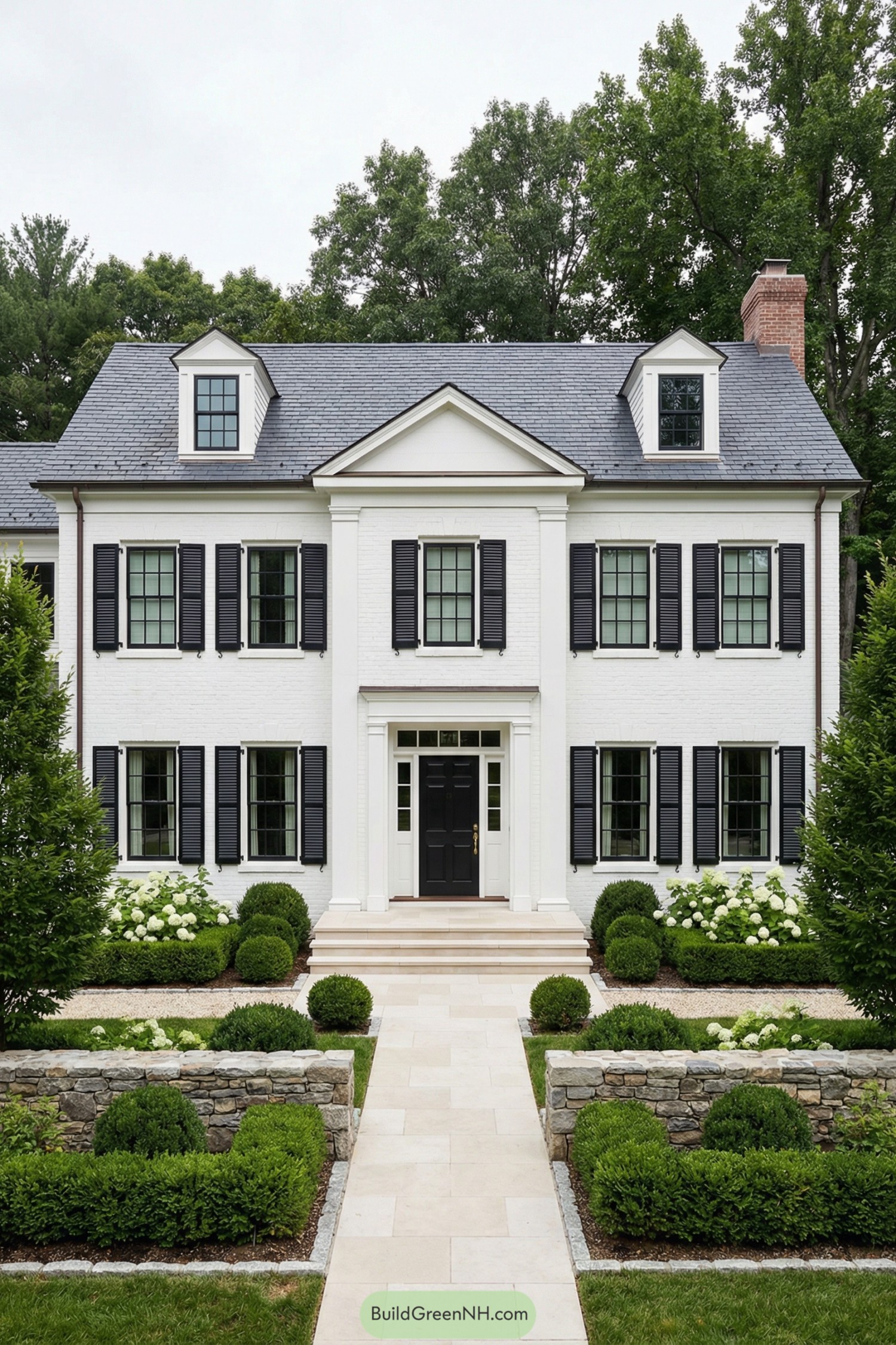 White brick colonial home with black shutters and a manicured formal front garden