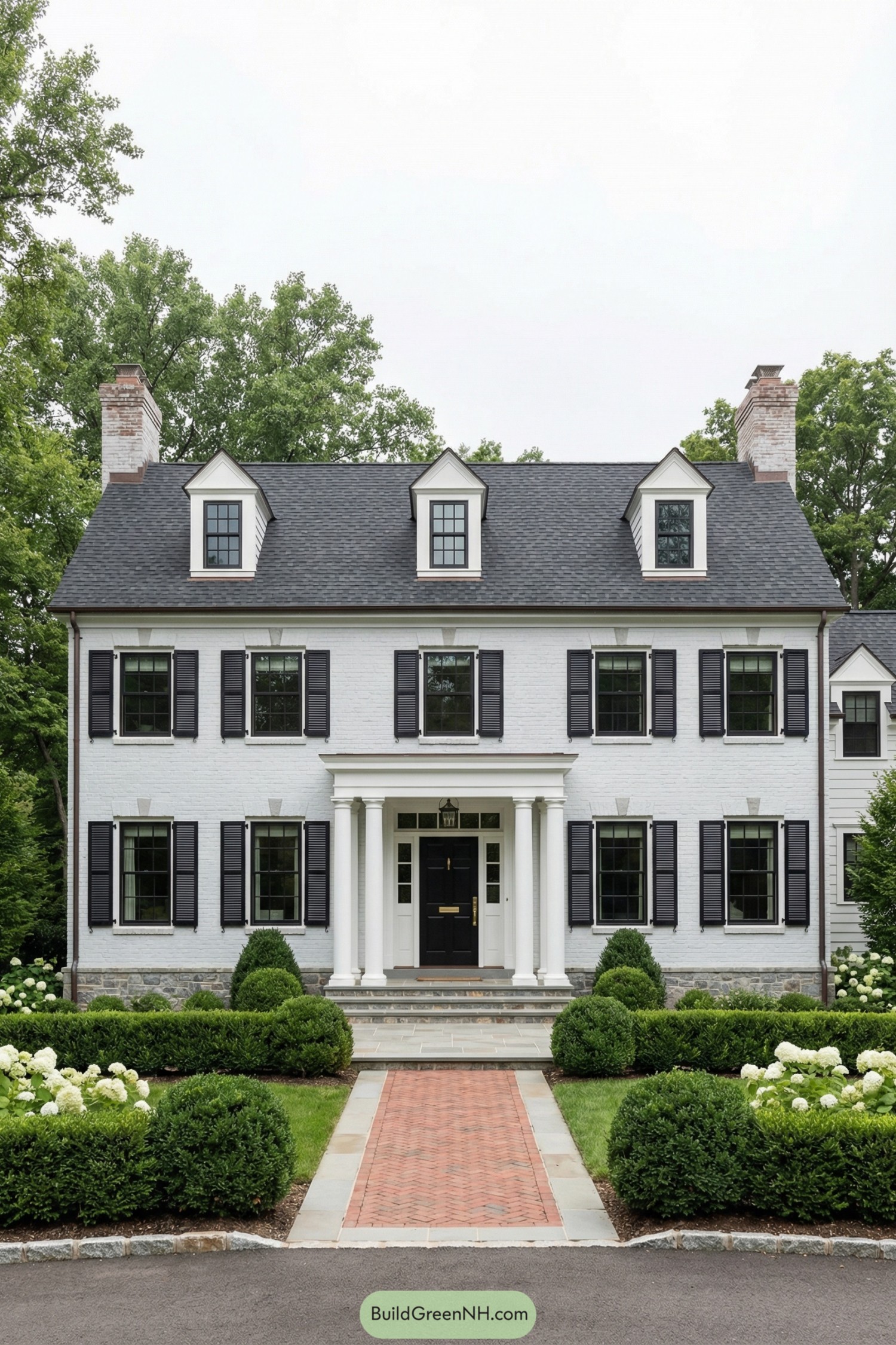 White brick colonial house with black shutters, central columned entry, and manicured front garden