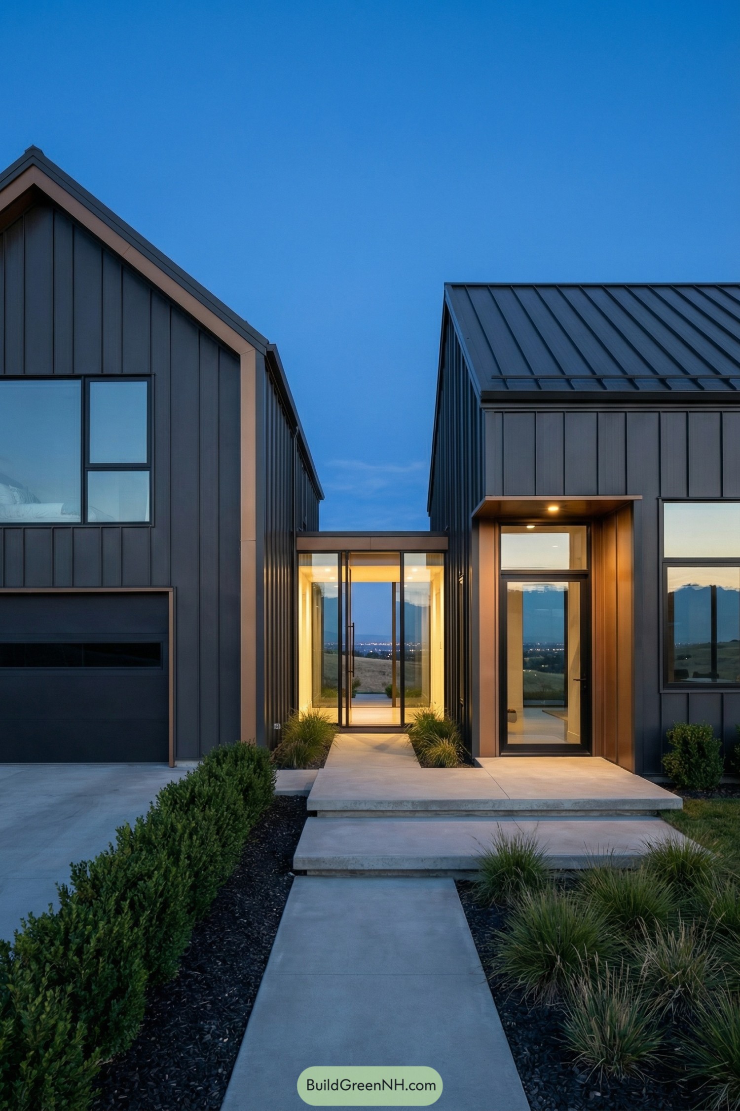 Modern barndominium with metal gables linked by a glass breezeway at dusk