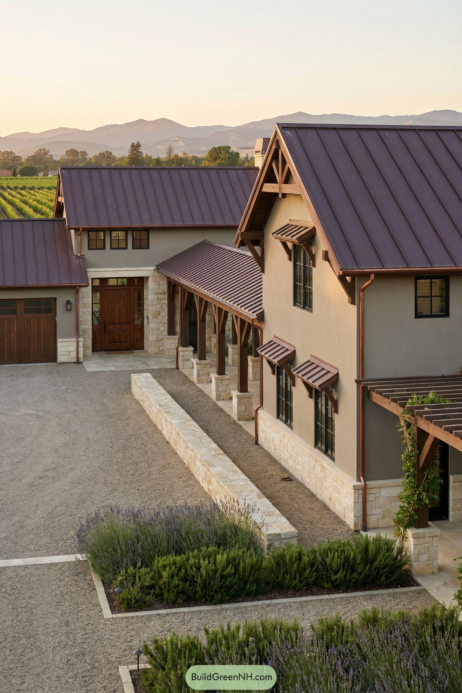 Warm-toned barndominium with metal roofs, stone base, and a covered breezeway overlooking distant vineyards and hills