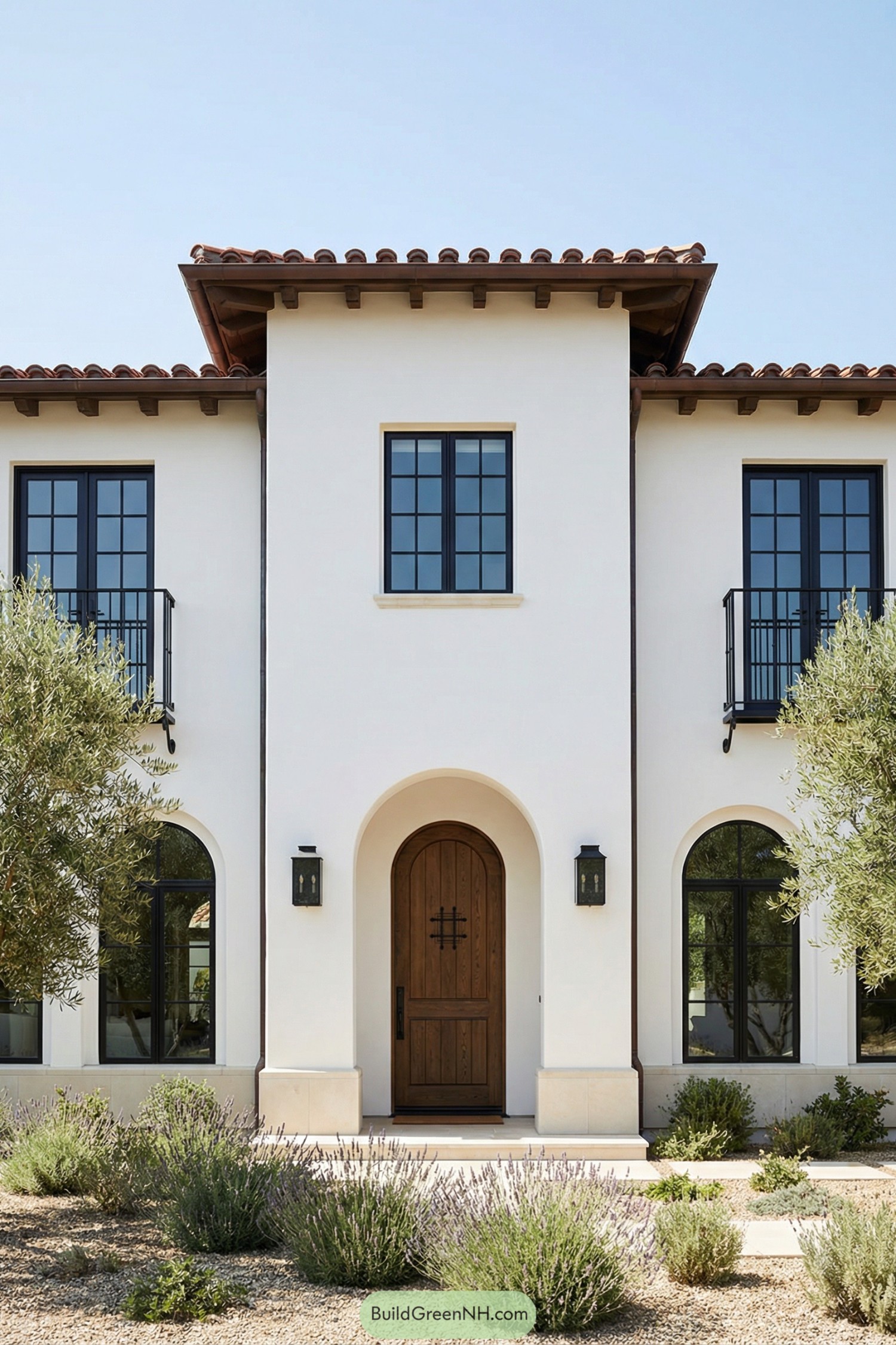 White stucco Mediterranean house with arched entry and dark windows