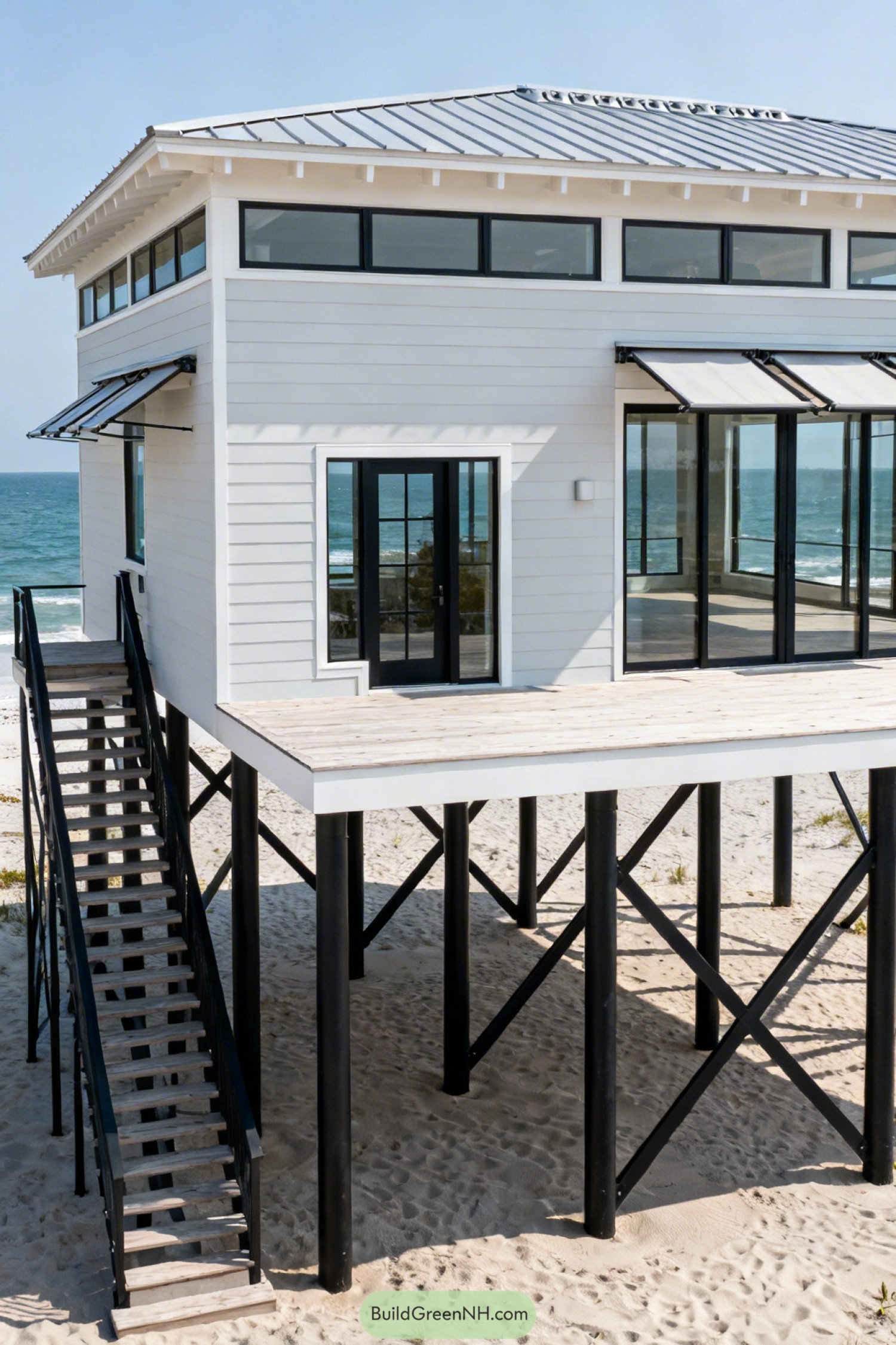 Modern stilted white beach house with metal roof and large glass doors overlooking the ocean