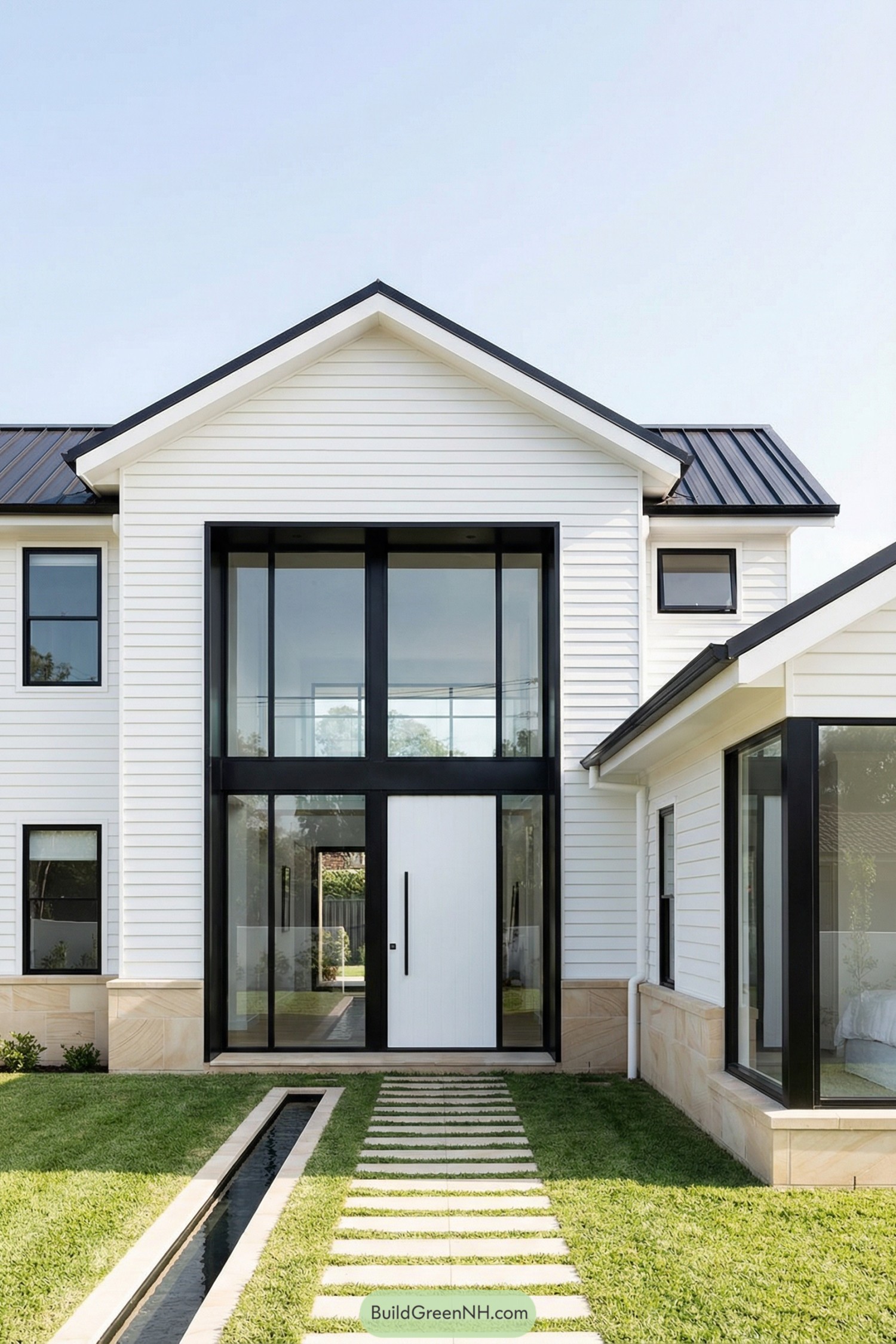 Modern white Hamptons house with tall black framed glass entry and stepping stone path