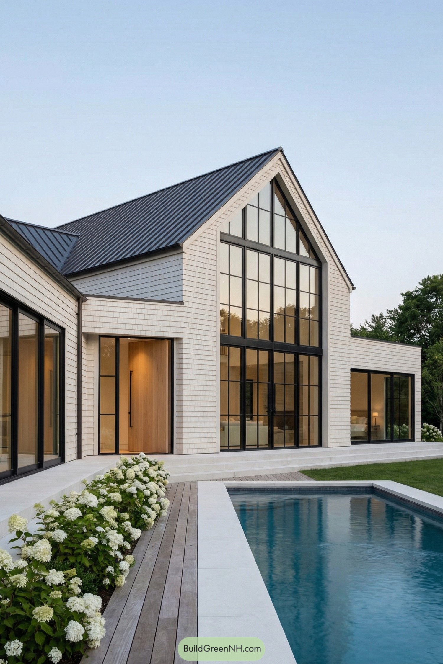 Modern Hamptons house with tall black framed windows beside a sleek pool