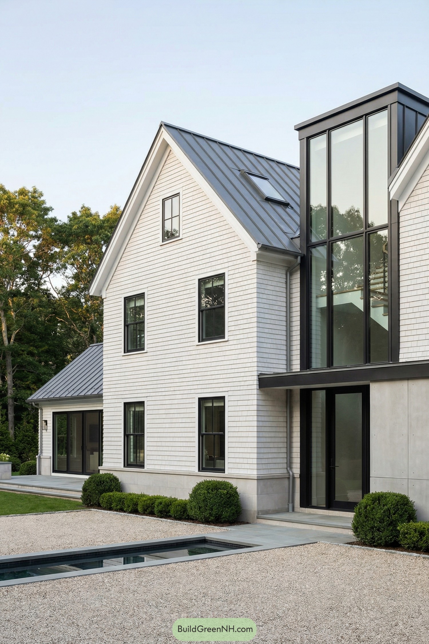 Modern white gabled house with tall glass volume beside a narrow courtyard pool