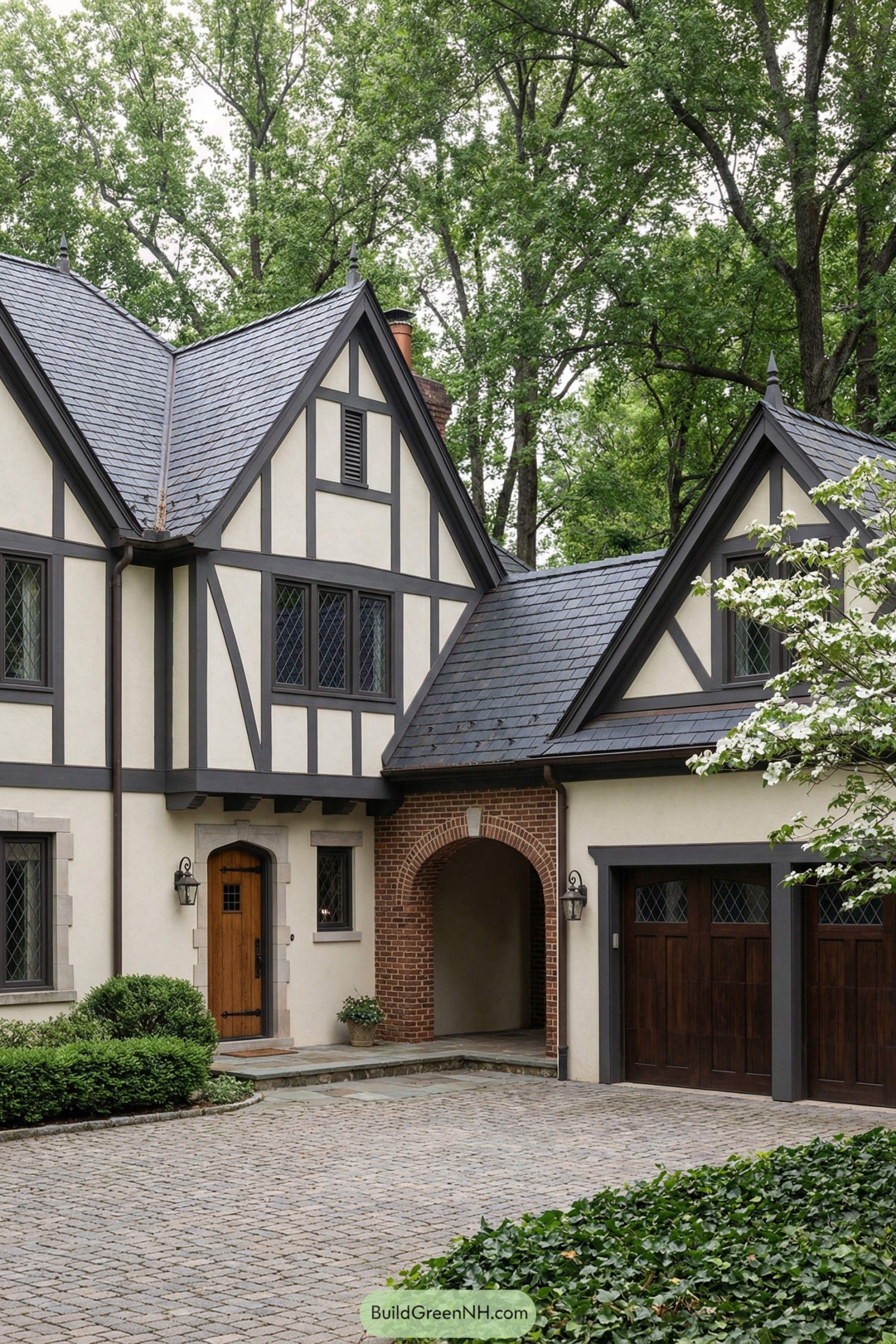 Tudor style home with arched brick breezeway and attached garage