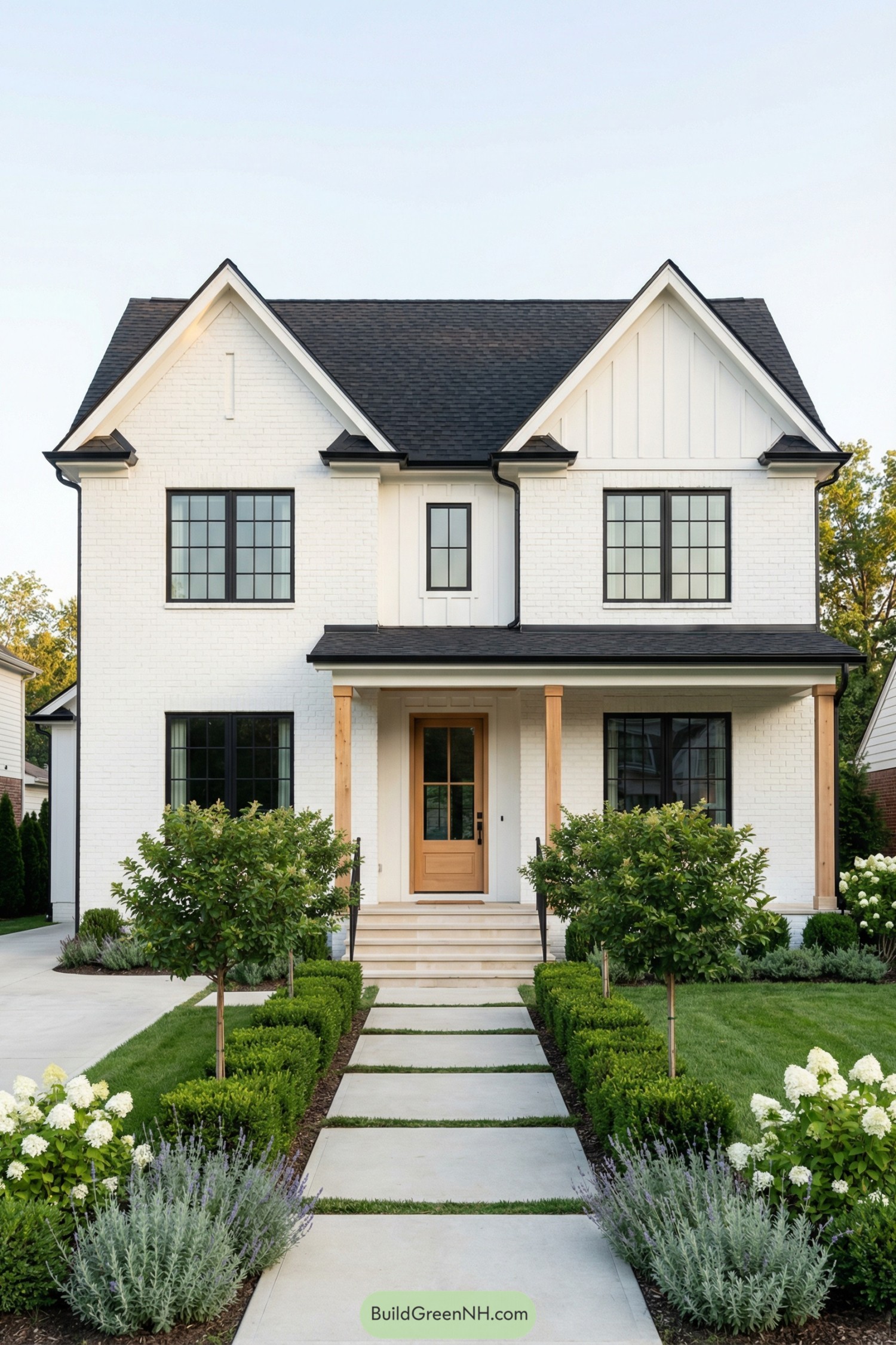 White two story gable house with black windows wood front door and neatly manicured front garden