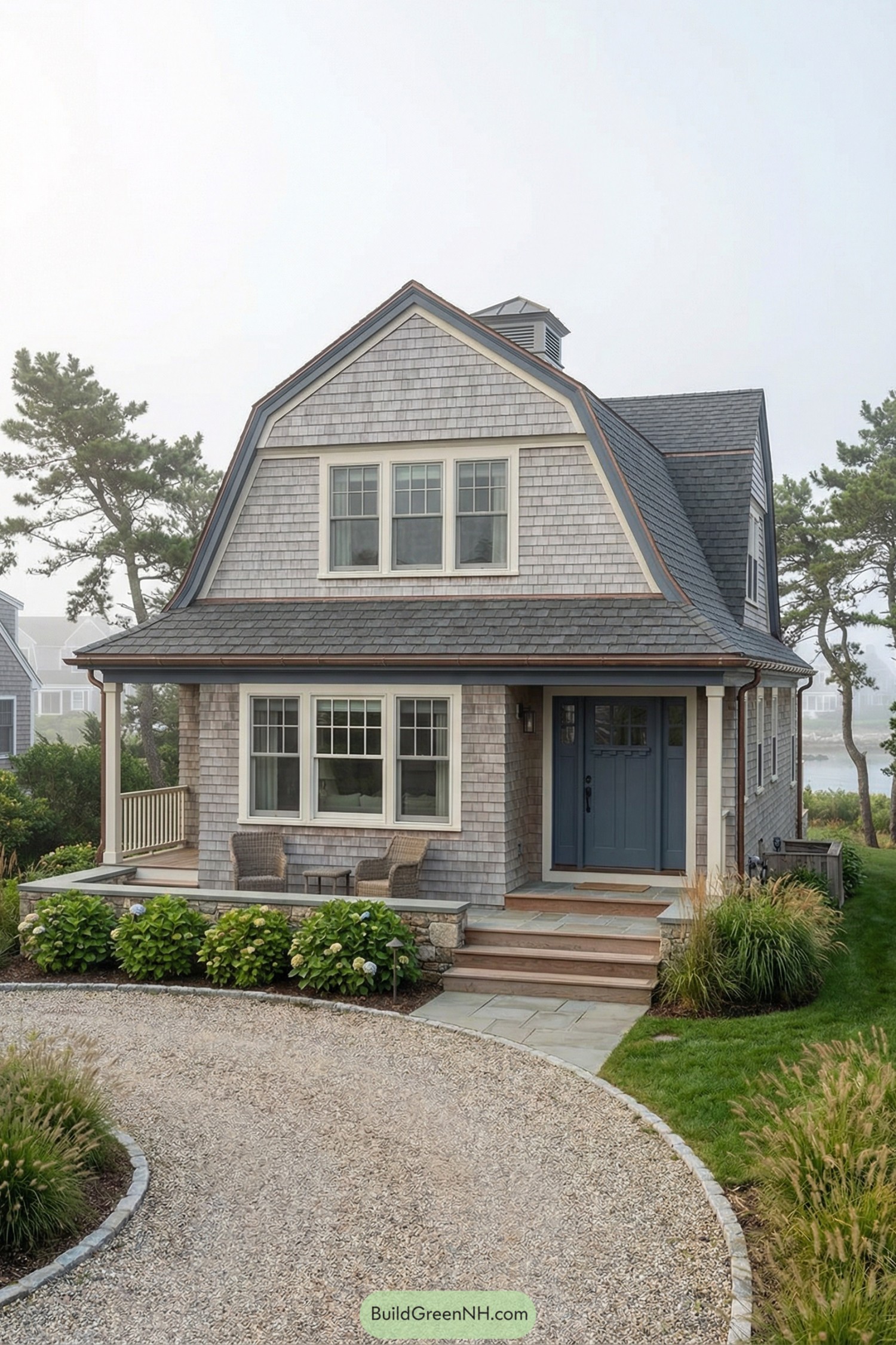 Small shingled gambrel cottage with blue door and curved gravel drive