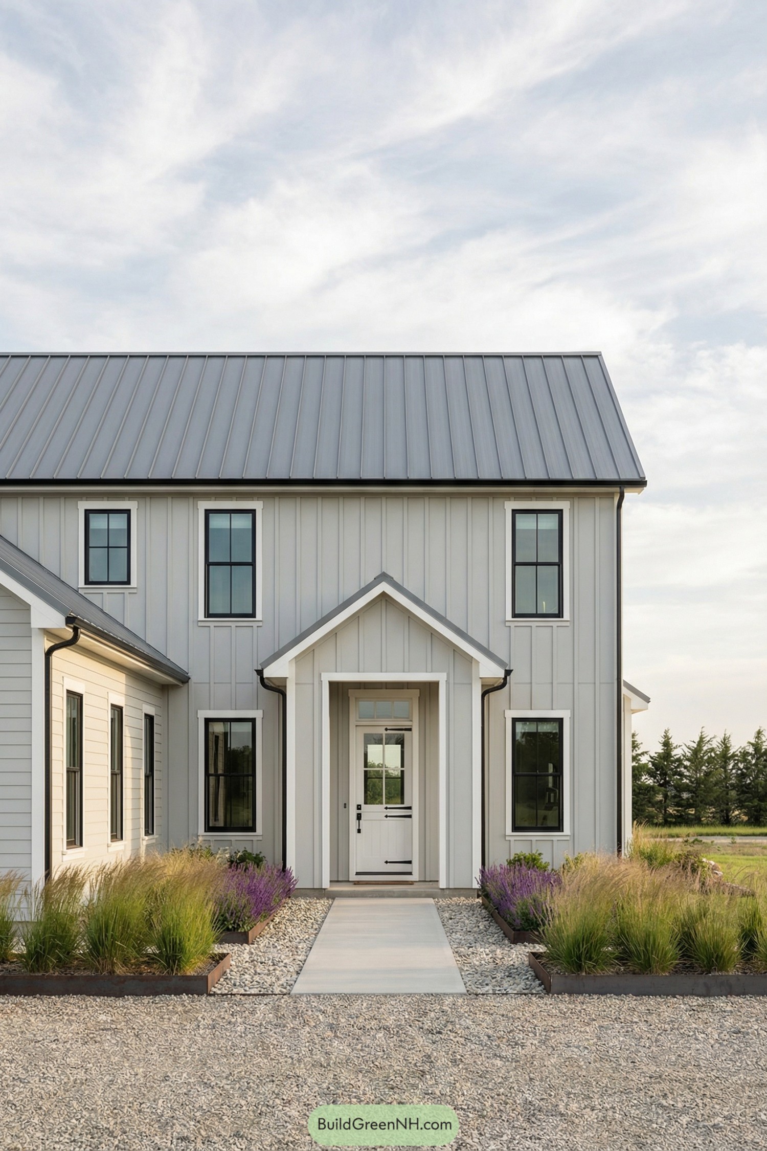 Modern gray farmhouse front with metal roof and gravel path