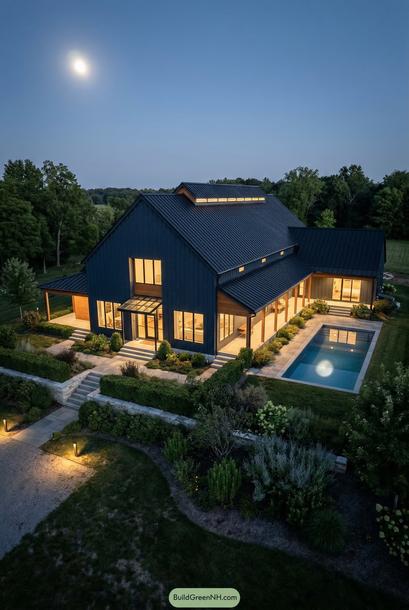Modern black barndominium with lap pool at dusk