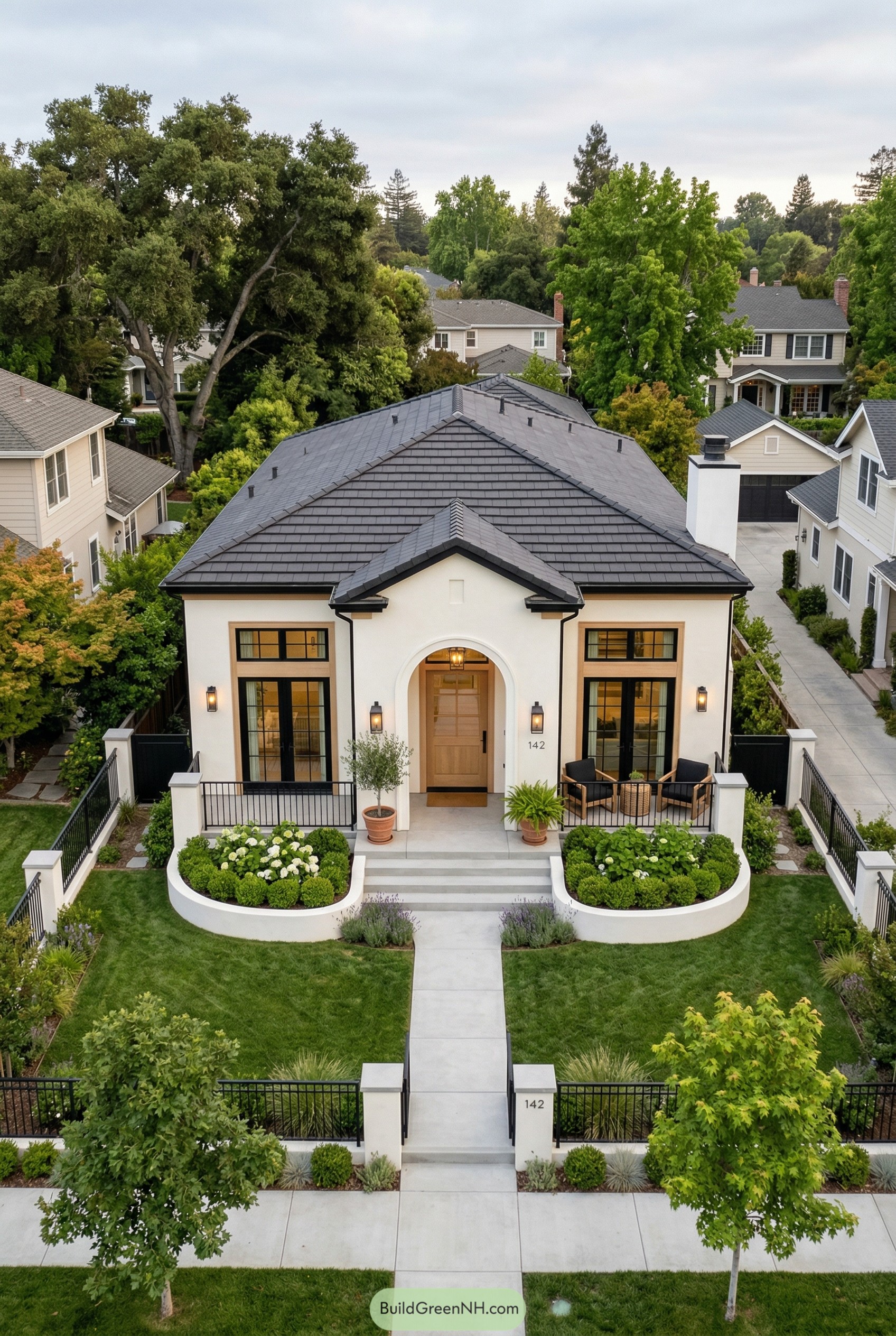 Single story white stucco house with dark hipped roof and arched entry