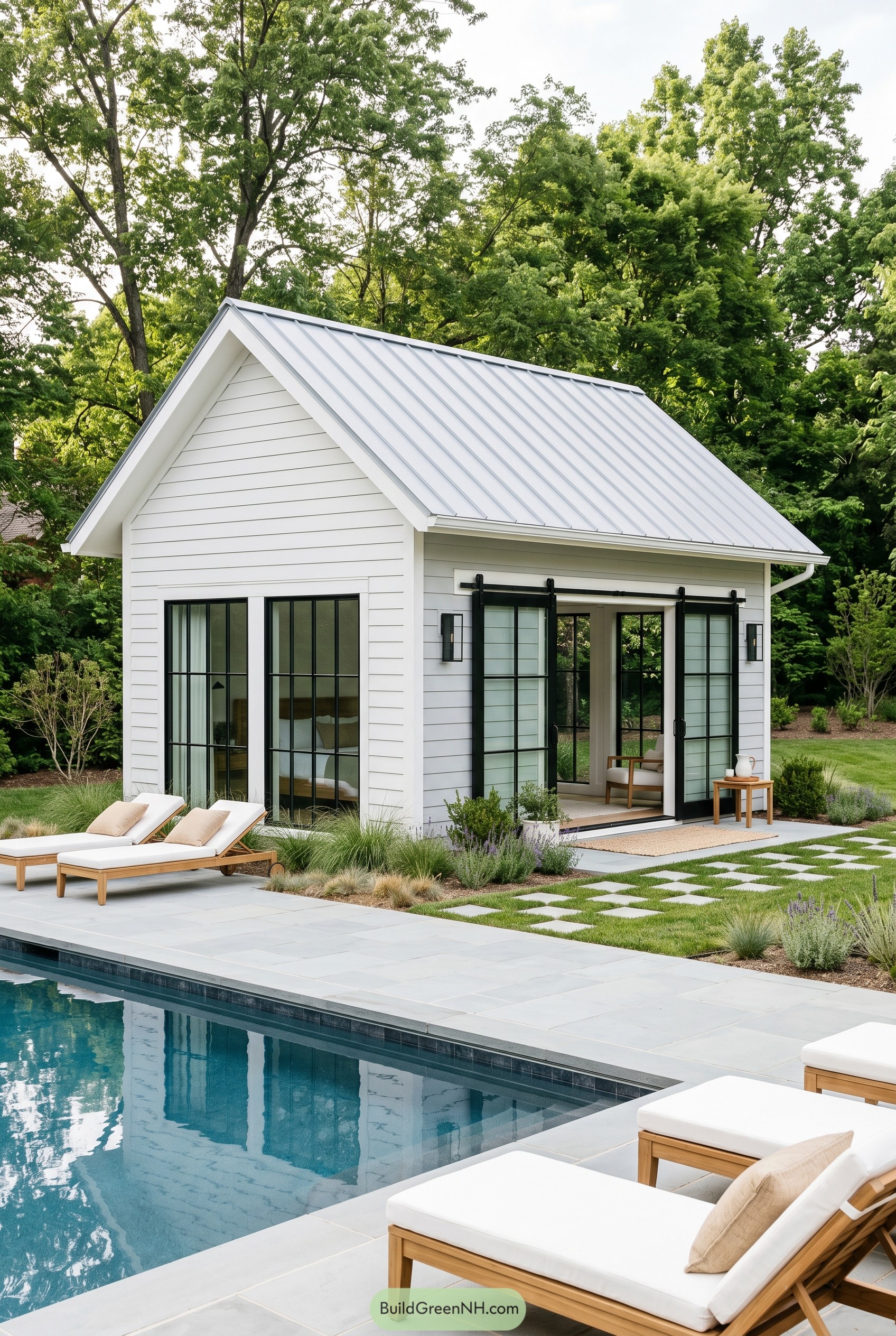White pool house with black sliding doors by a pool